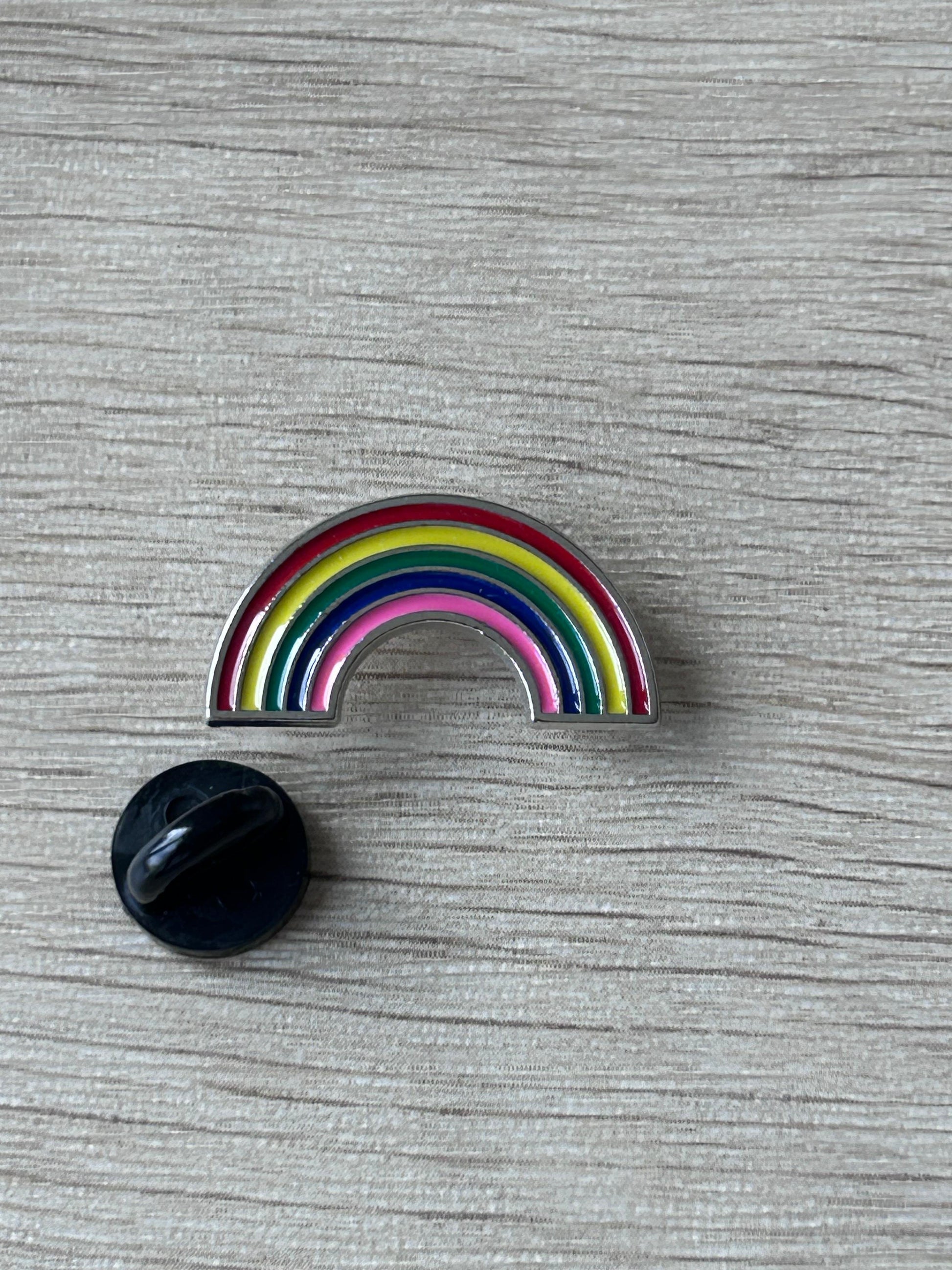 Épingle arc-en-ciel en forme d’arc, rayures multicolores, avec dos noir.