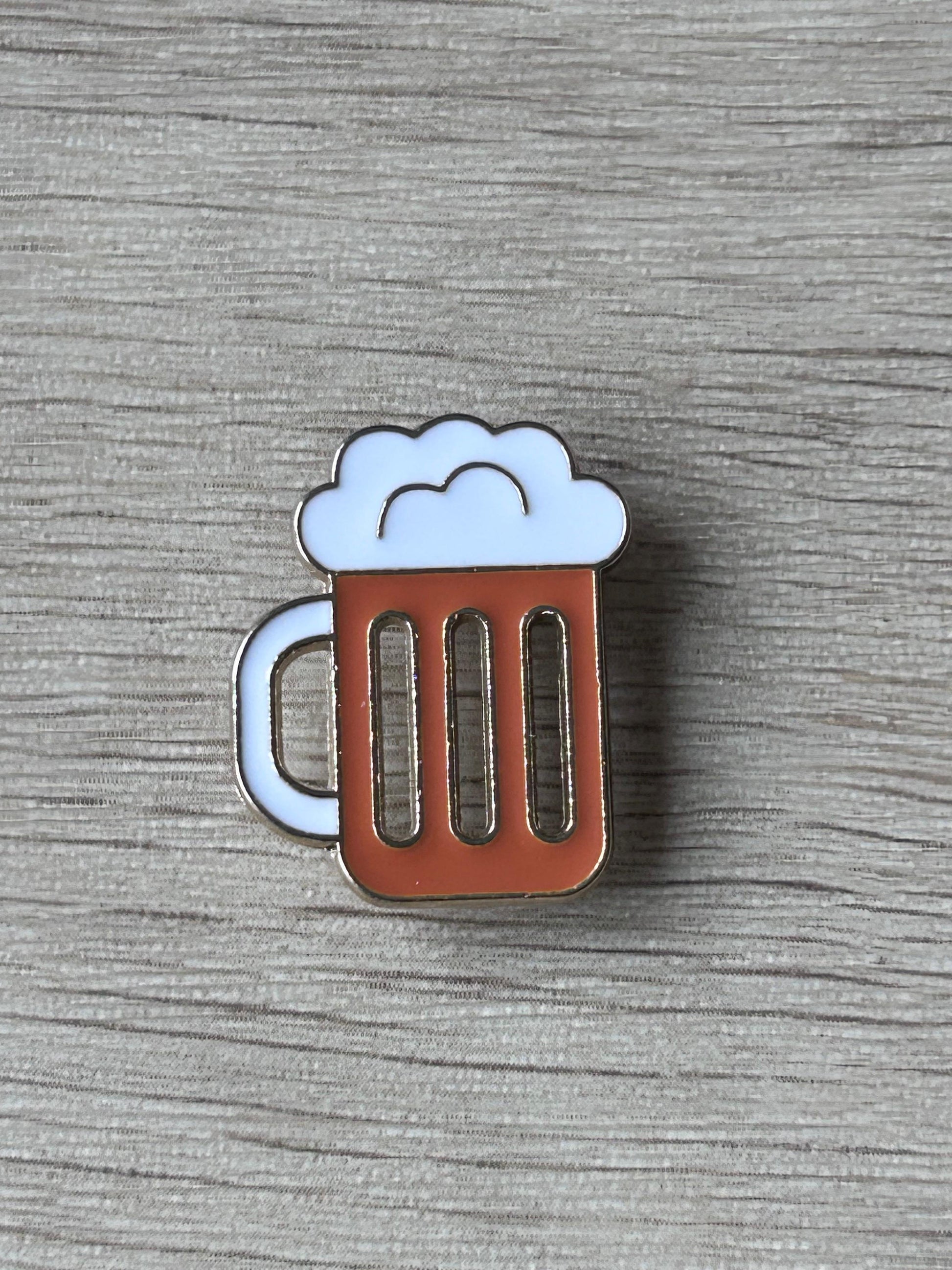 Pin's chope de bière: mousse blanche, corps brun à trois barres, contour argenté.