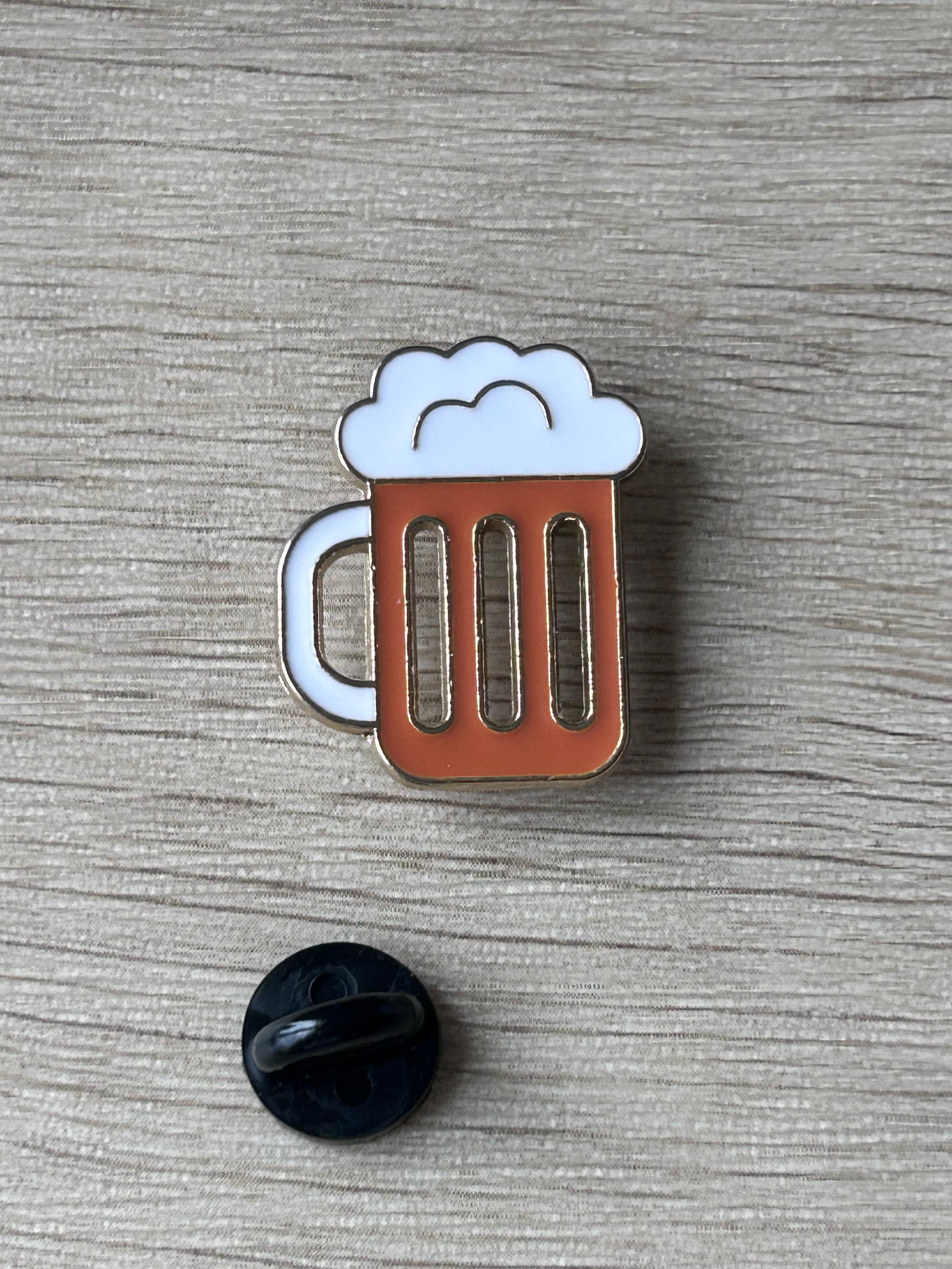 Pin's chope de bière émaillée: mousse blanche, corps brun, contours argentés.