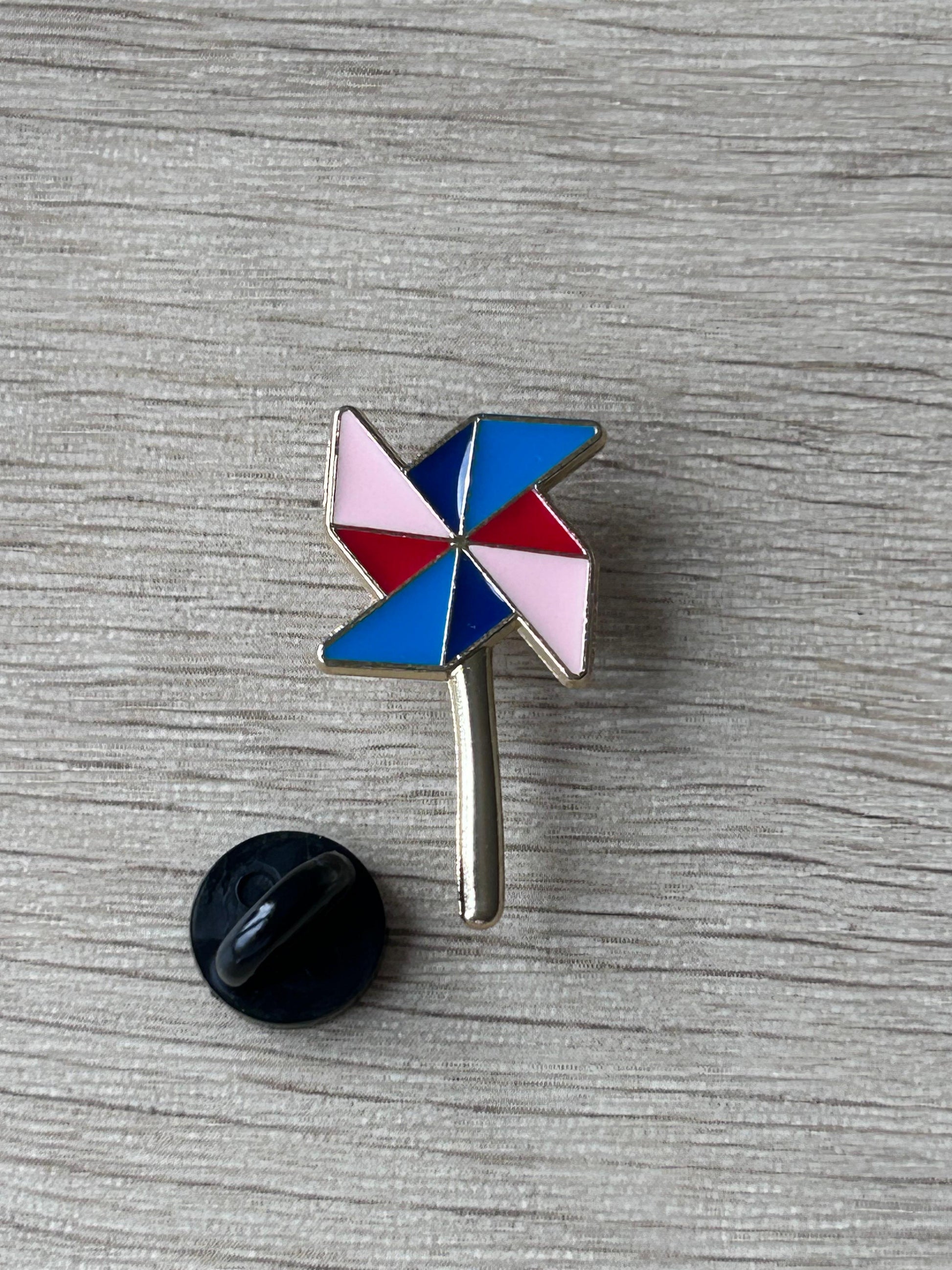 Pin's moulin à vent multicolore avec tige métallique et dos noir, motifs bleu et rouge