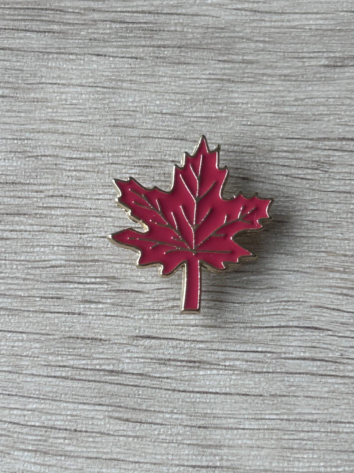 Broche feuille d’érable rouge émaillée, bord argenté et tige verticale.