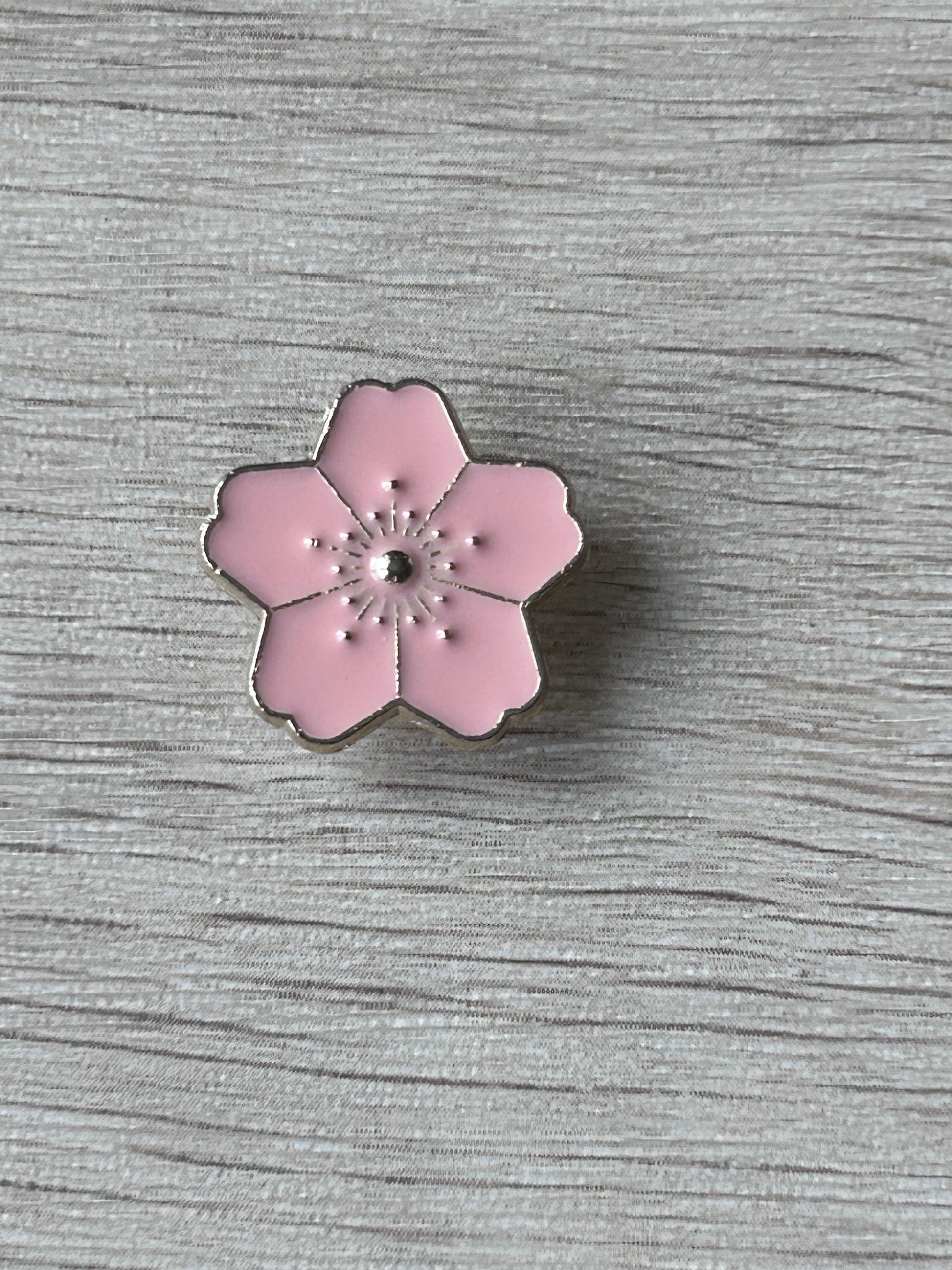 Broche fleur de cerisier rose émaillée à bord noir et centre étoilé