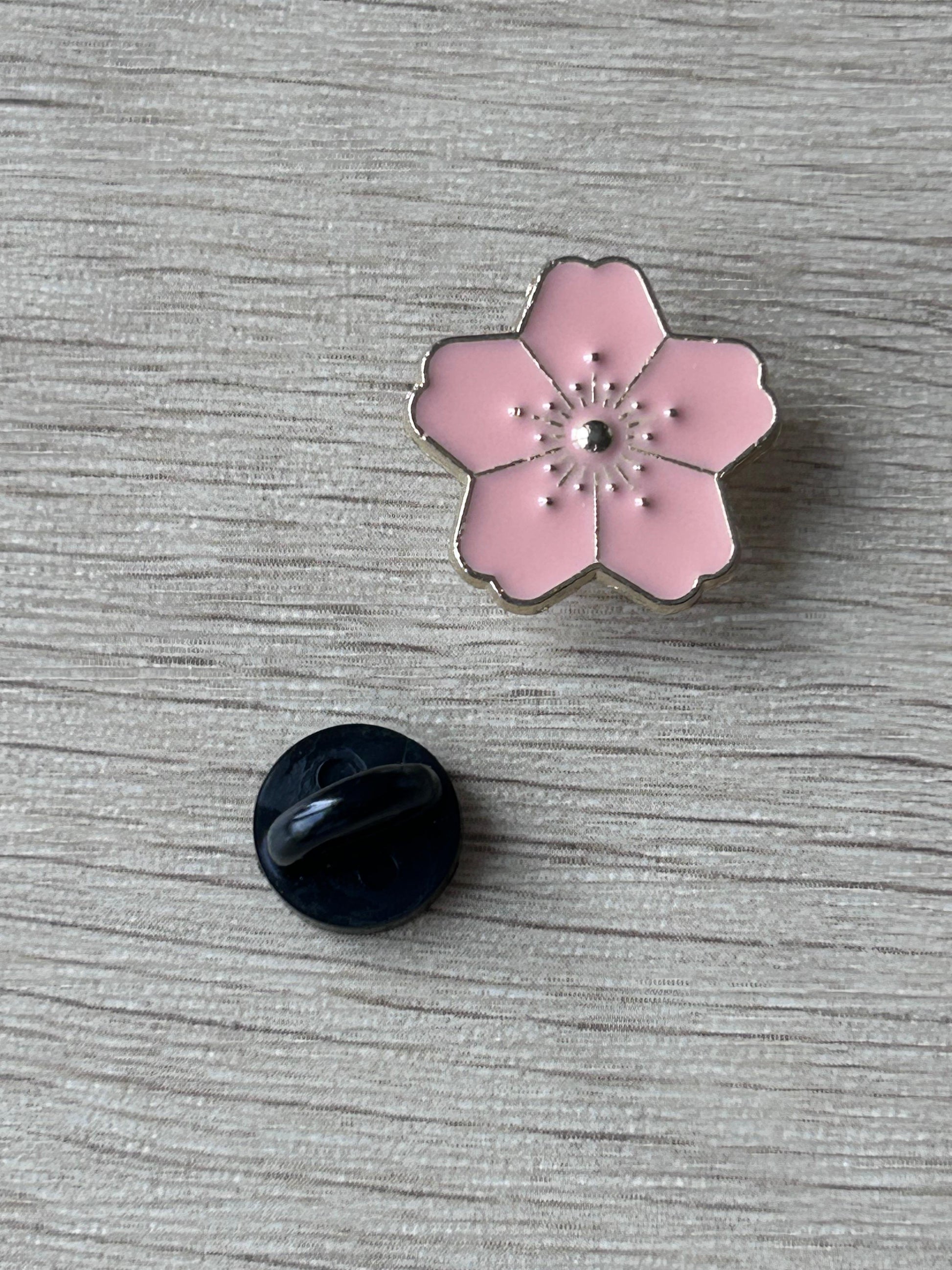 Broche fleur de cerisier rose avec bord noir et centre, dos noir rond visible