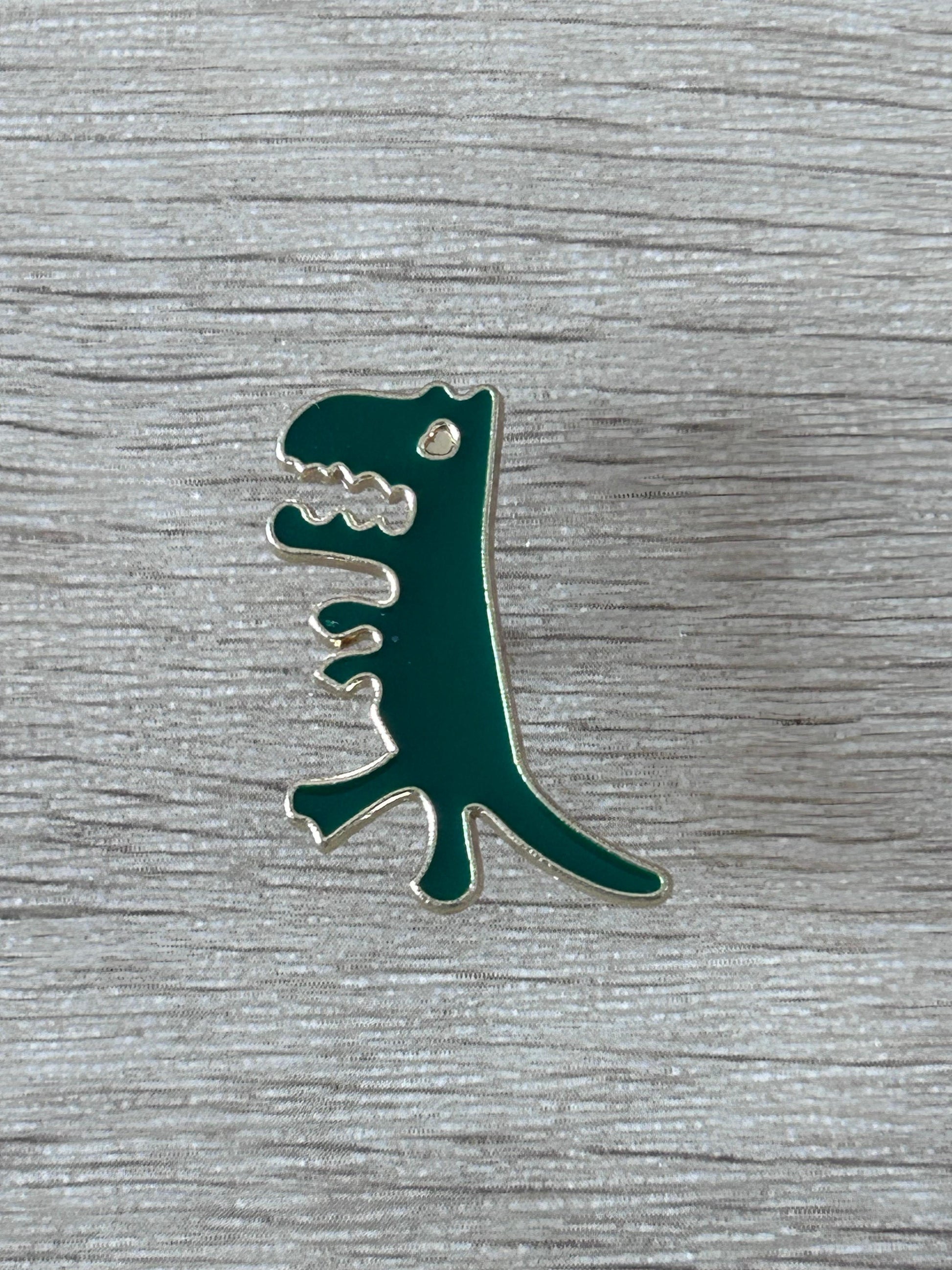 Broche T-Rex verte avec détails argentés, forme de dinosaures.