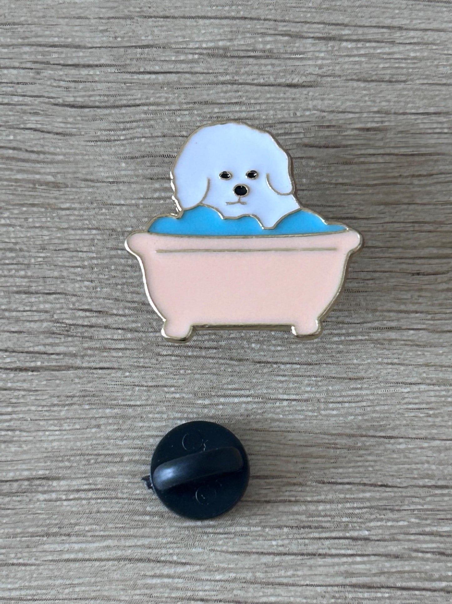 Pin's chien blanc dans baignoire rose-bleu, avec dos noir en rond.