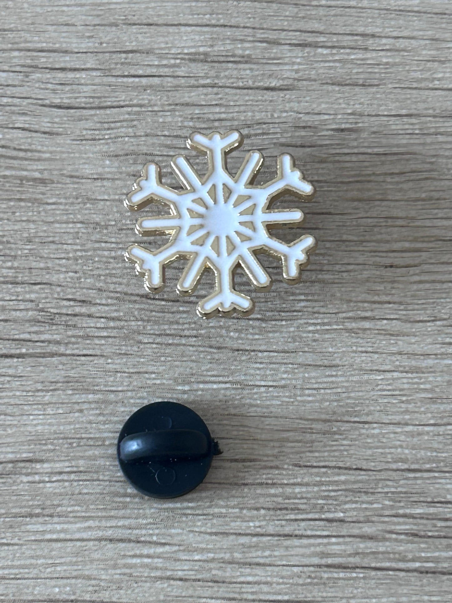 Broche flocon de neige argenté à centre blanc, avec embout noir rond.