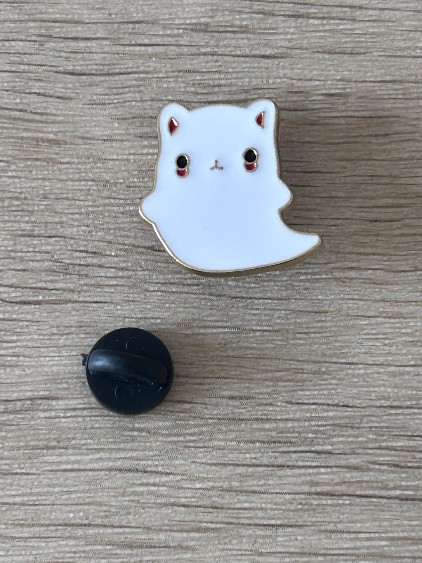 Épingle chat fantôme émaillée, tête blanche avec yeux rouges et pattes marron, dos noir.