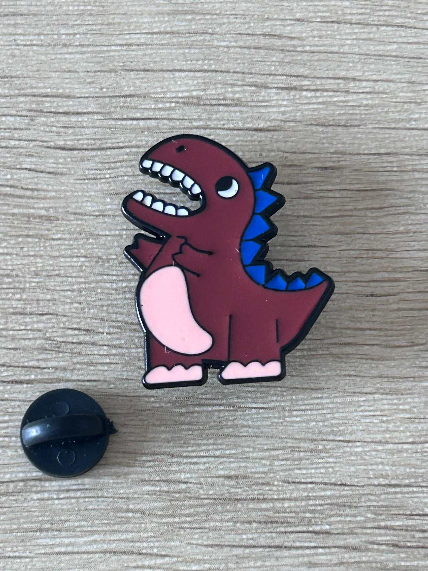 Pin T-Rex bordeaux en colère, bouche ouverte, pointes bleues, avec attache noire en plastique
