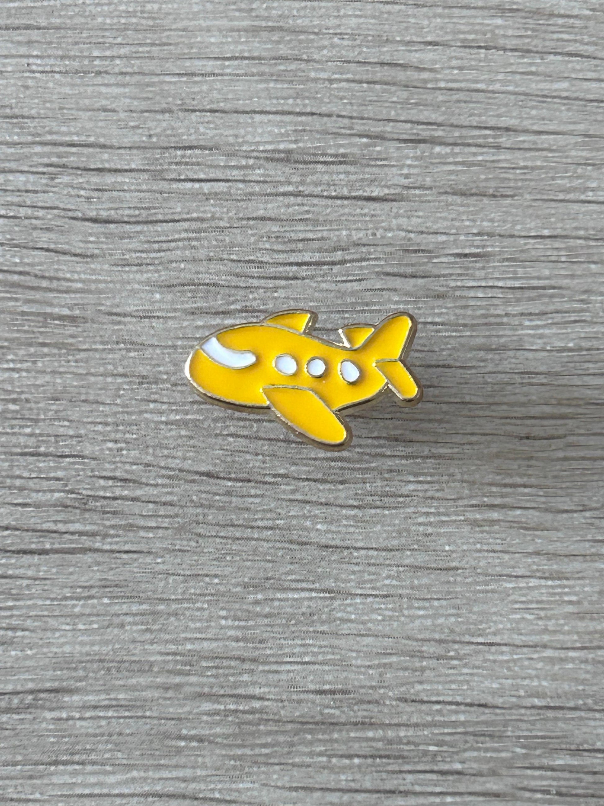 Broche avion jaune kawaii en métal, émail blanc et détails ronds.