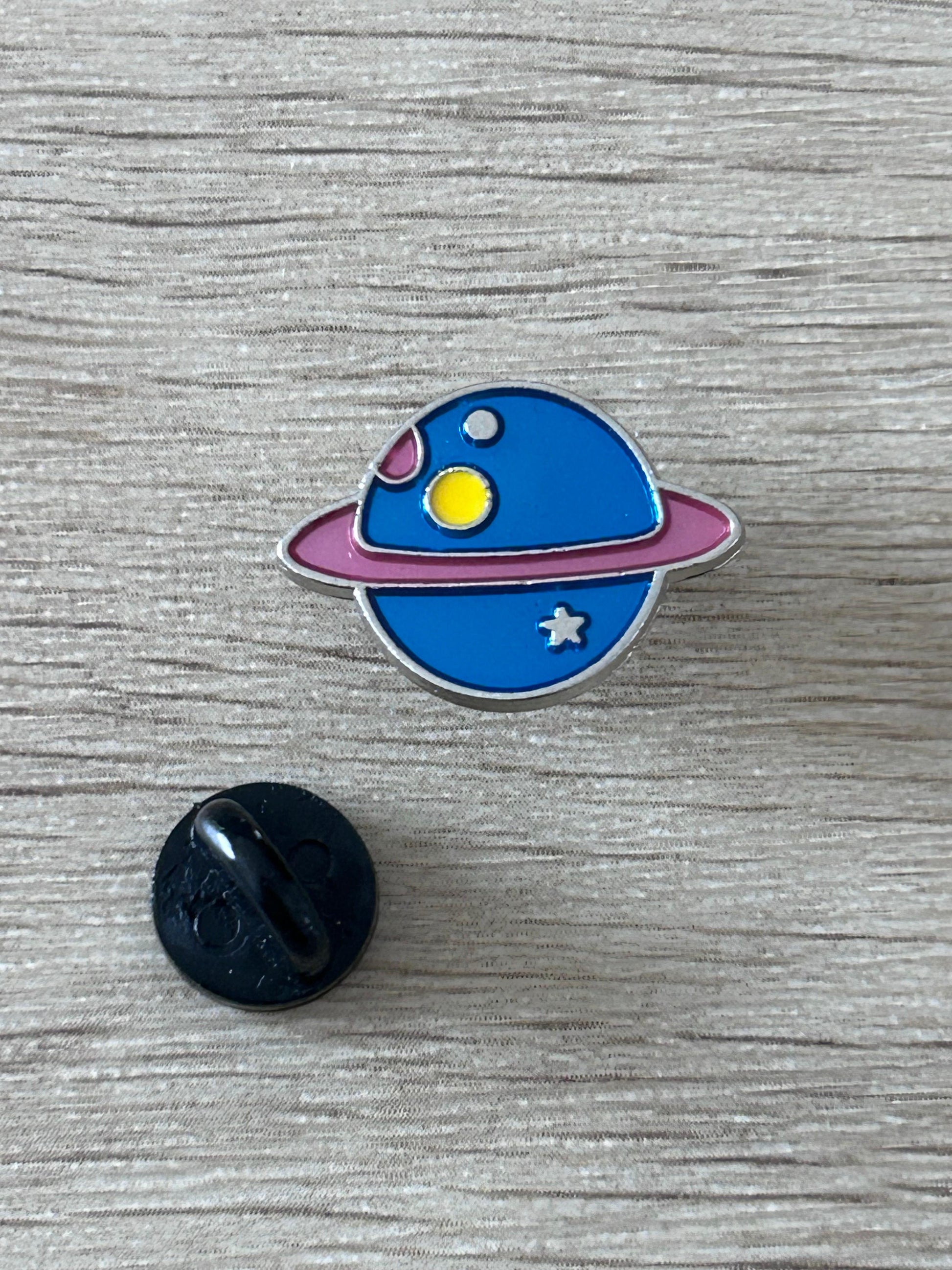 Broche émaillée planète bleue aux anneaux, étoile et soleil jaunes, dos noir