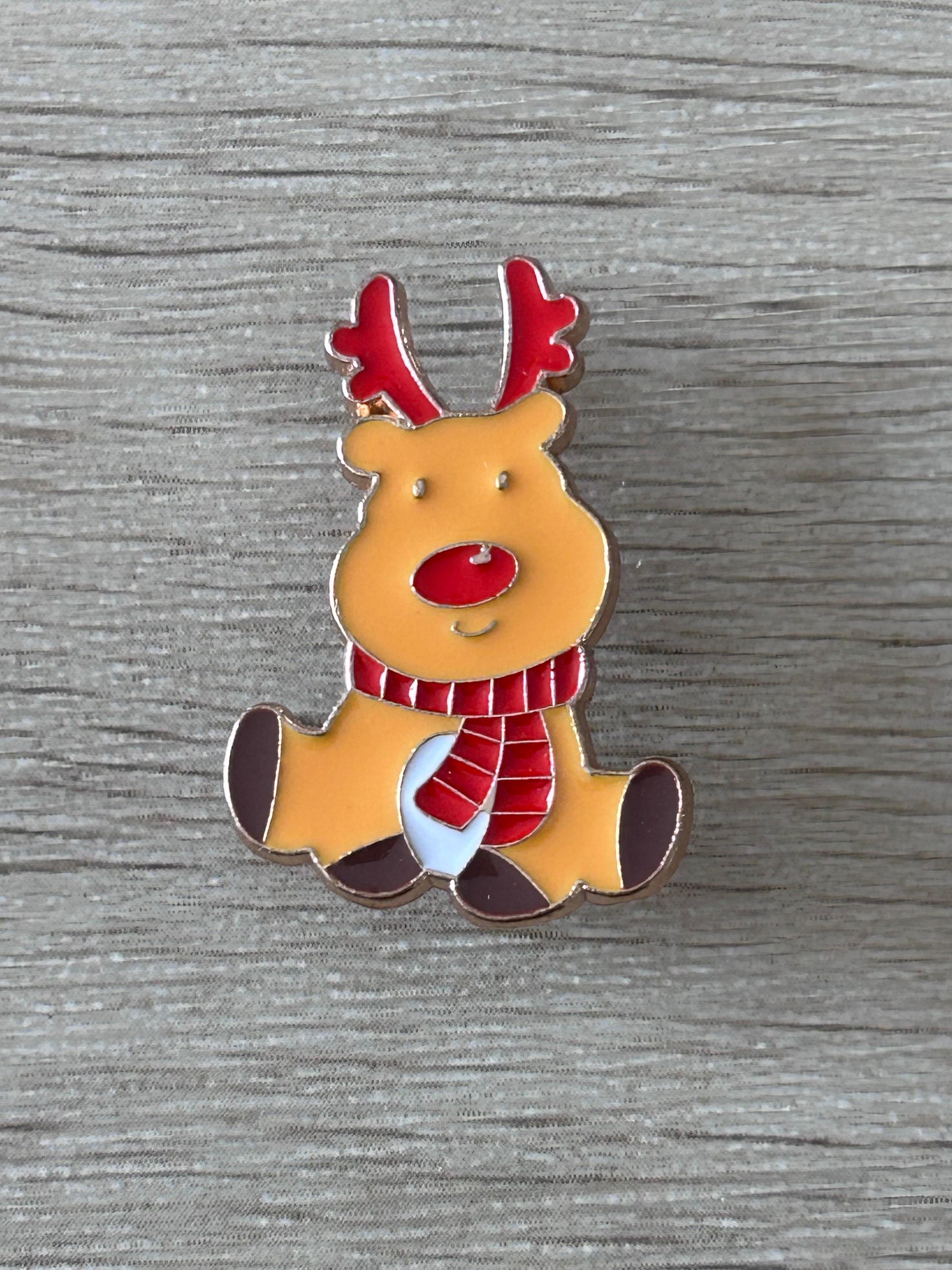 Épingle renne de Noël kawaii jaune, cornes rouges, écharpe et nœud rouge.