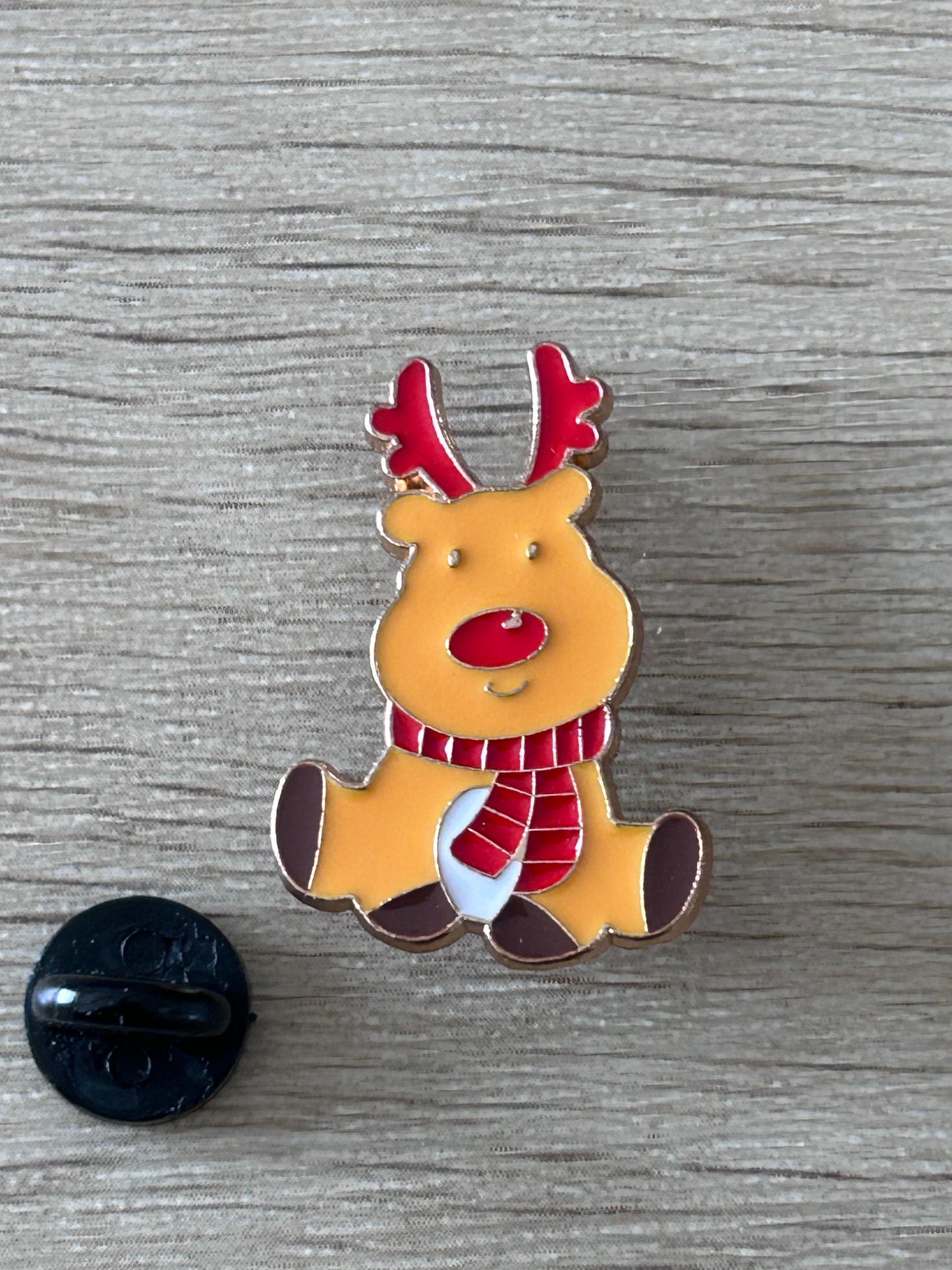 Épingle renne de Noël kawaii jaune, cornes rouges, écharpe rayée et nœud rouge.