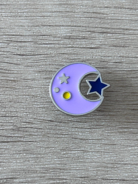Pin's rond lilas avec lune et étoiles, petit point jaune.