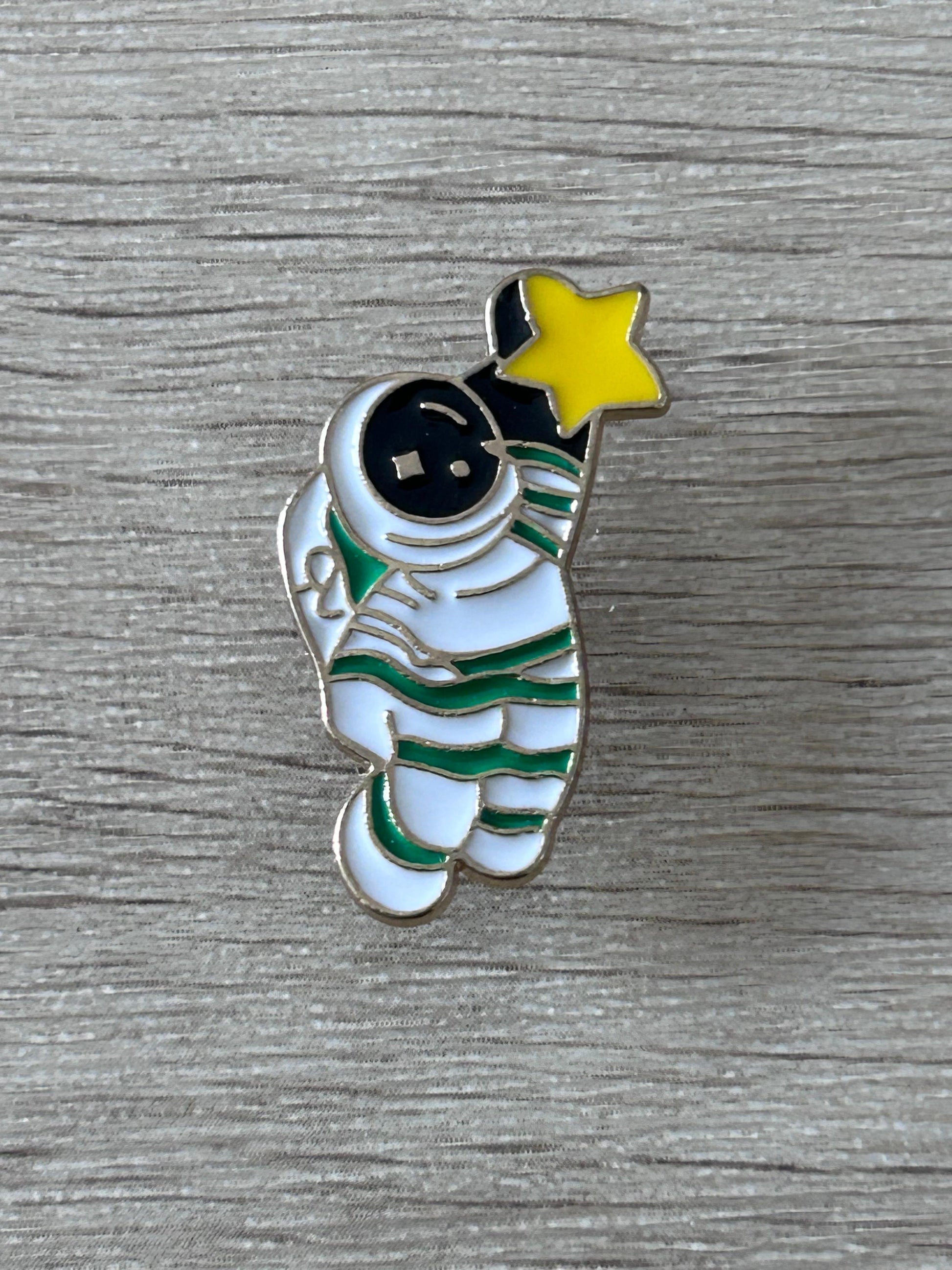 Pin en émail astronaute avec étoile jaune, combinaison blanche et rayures vertes