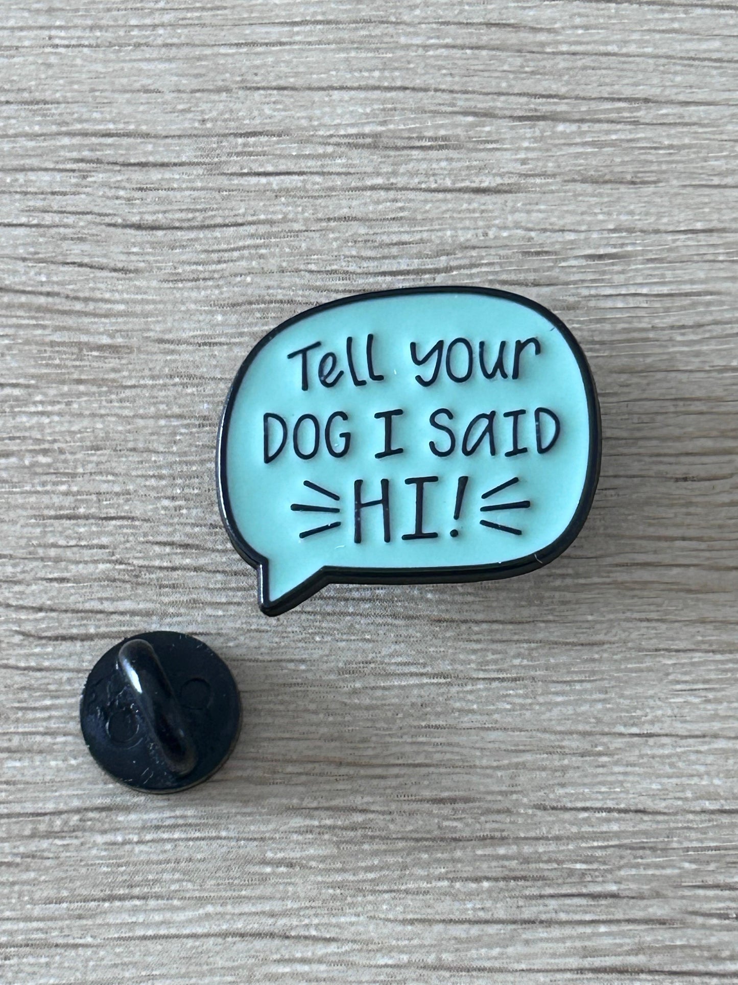 Épinglette bulle bleue « Tell your DOG I SAID HI! », avec attache noire visible