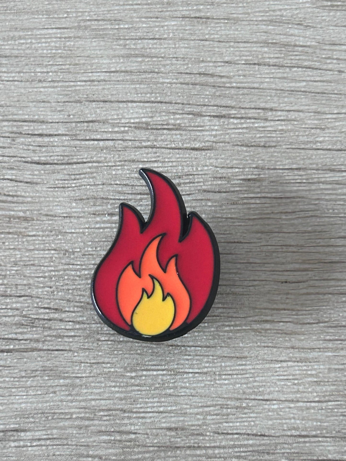Pin's en forme de flamme rouge et jaune, contour noir