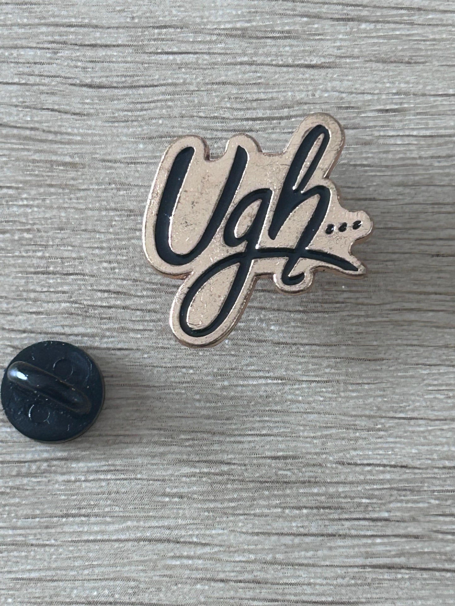 Pin 'Ugh...' émaillé noir et beige avec dos noir.