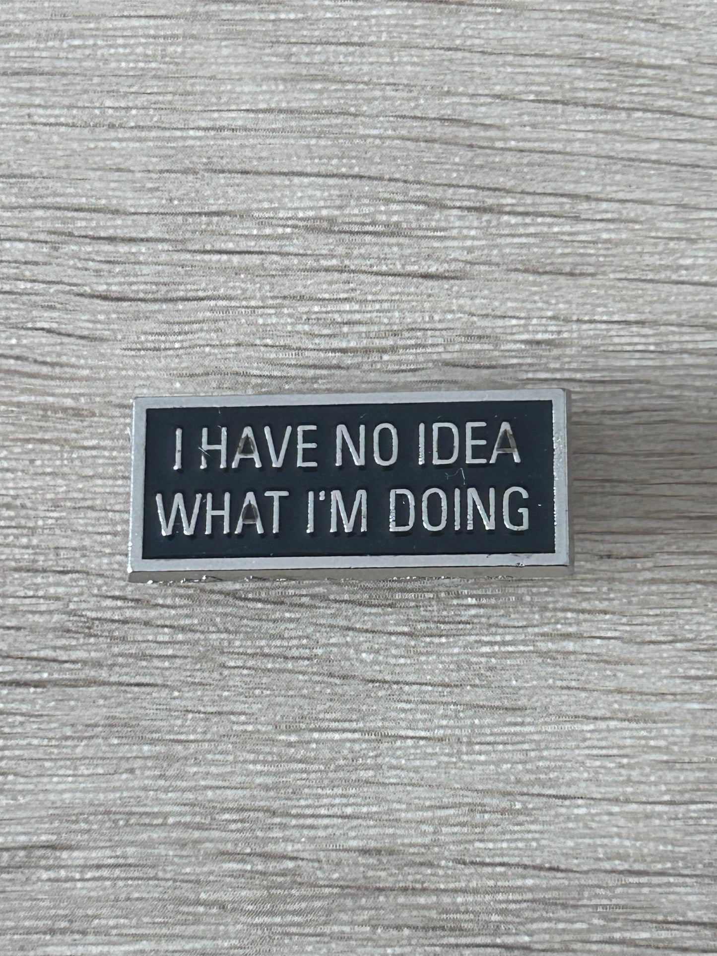 Épinglette noire rectangulaire avec texte « I HAVE NO IDEA WHAT I'M DOING »