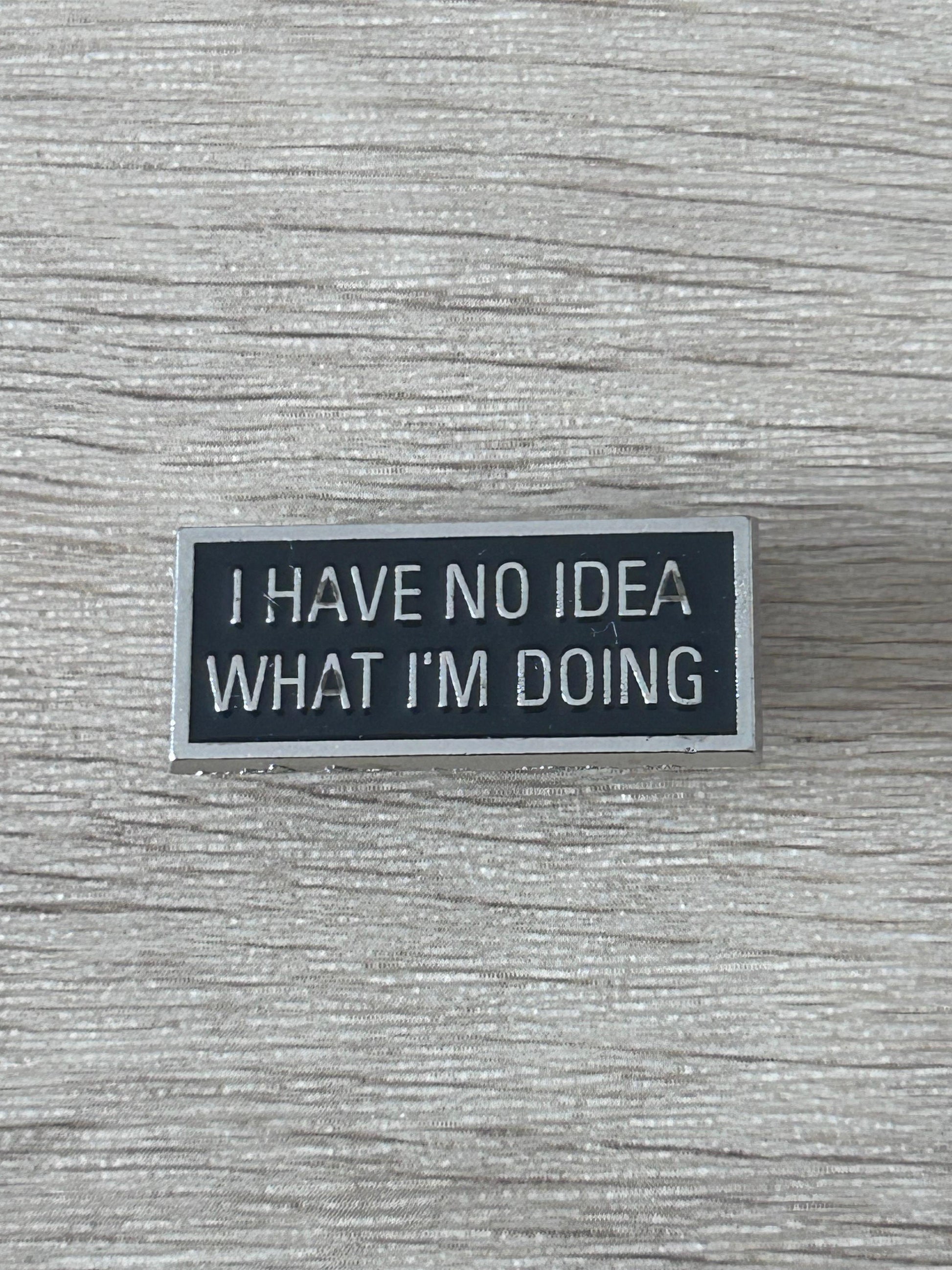 Épinglette noire rectangulaire avec texte « I HAVE NO IDEA WHAT I'M DOING »