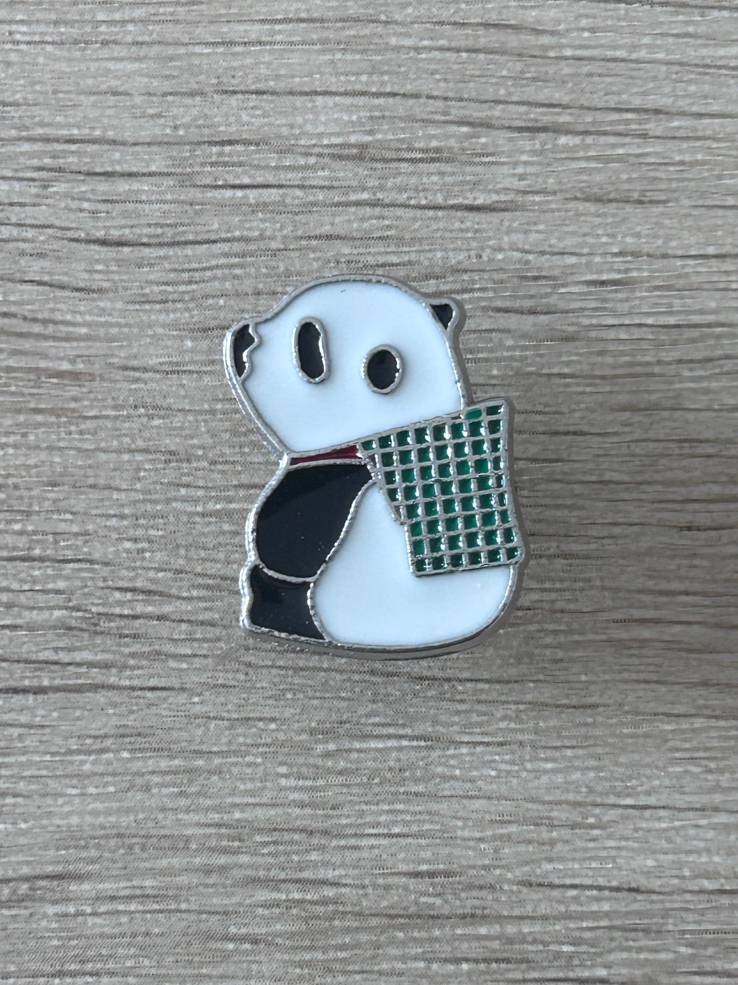 Épingle panda en émail, panier grillagé vert, yeux et pattes noirs sur bleu clair.