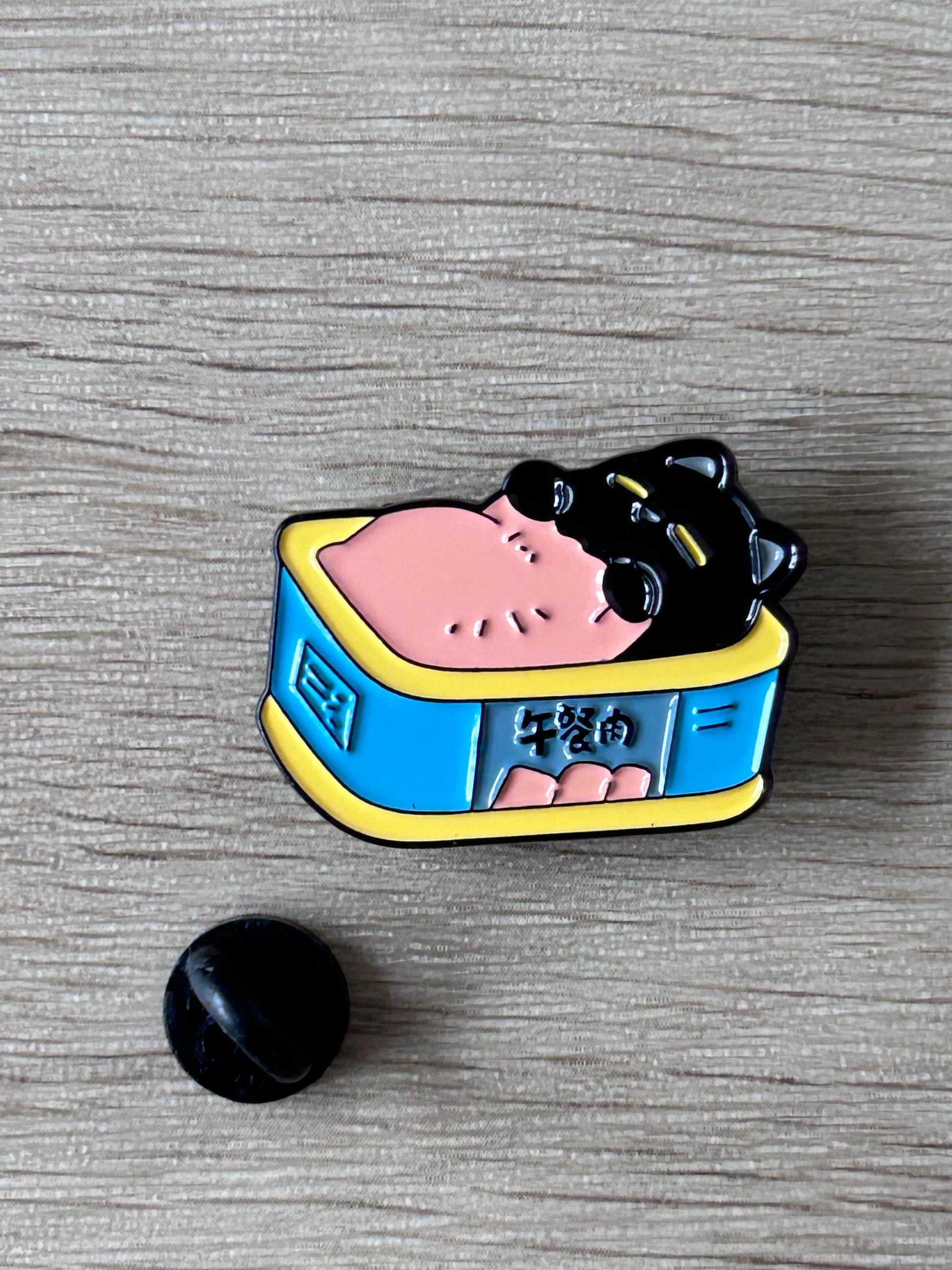 Pin émail chat noir dans boîte bleue bord jaune, vue rapprochée