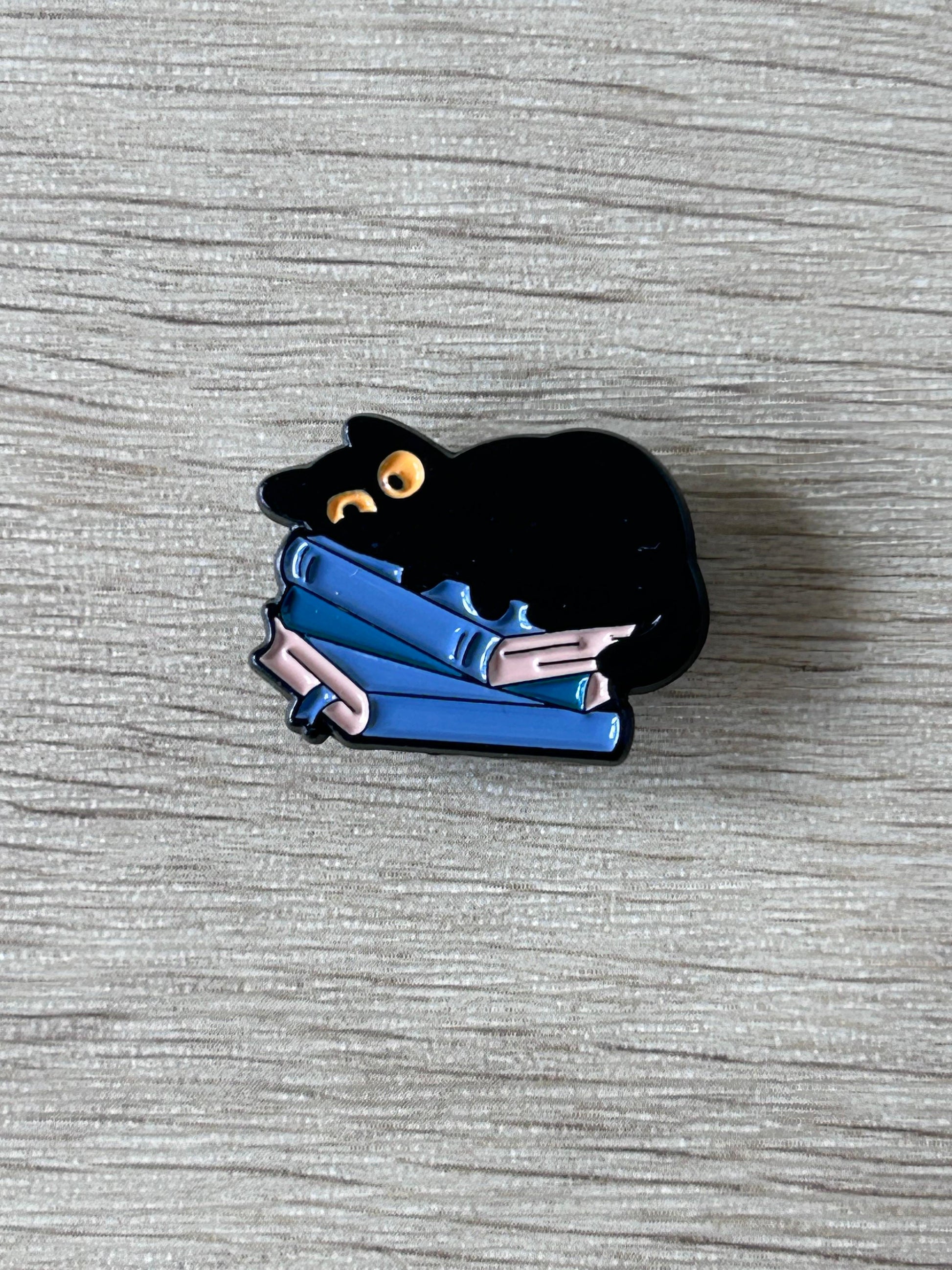 Pin chat noir tenant des livres bleus, petite épingle émaillée.