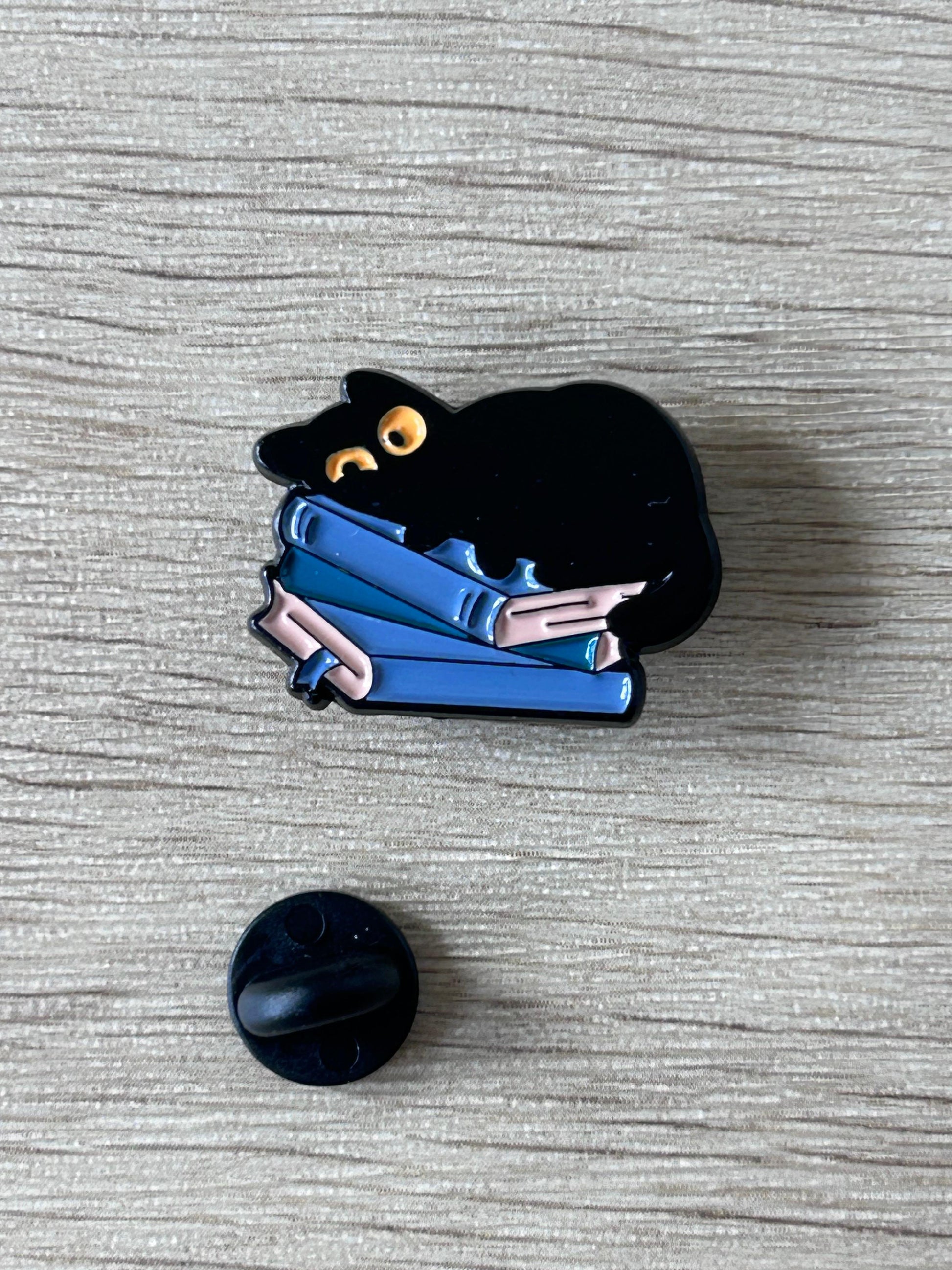 Pin chat noir et livres bleus avec attache noire en plastique