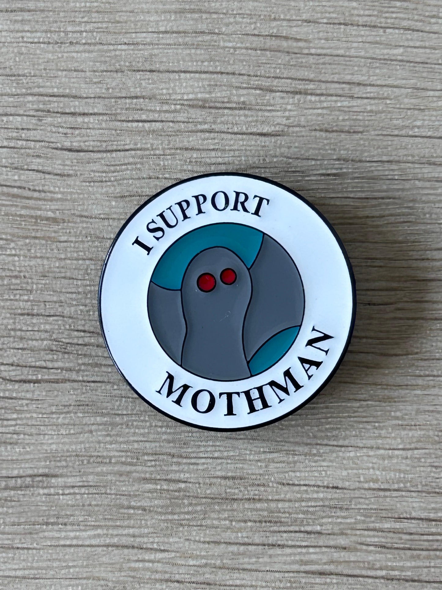 Badge en émail rond I SUPPORT MOTHMAN, personnage gris yeux rouges, contour noir