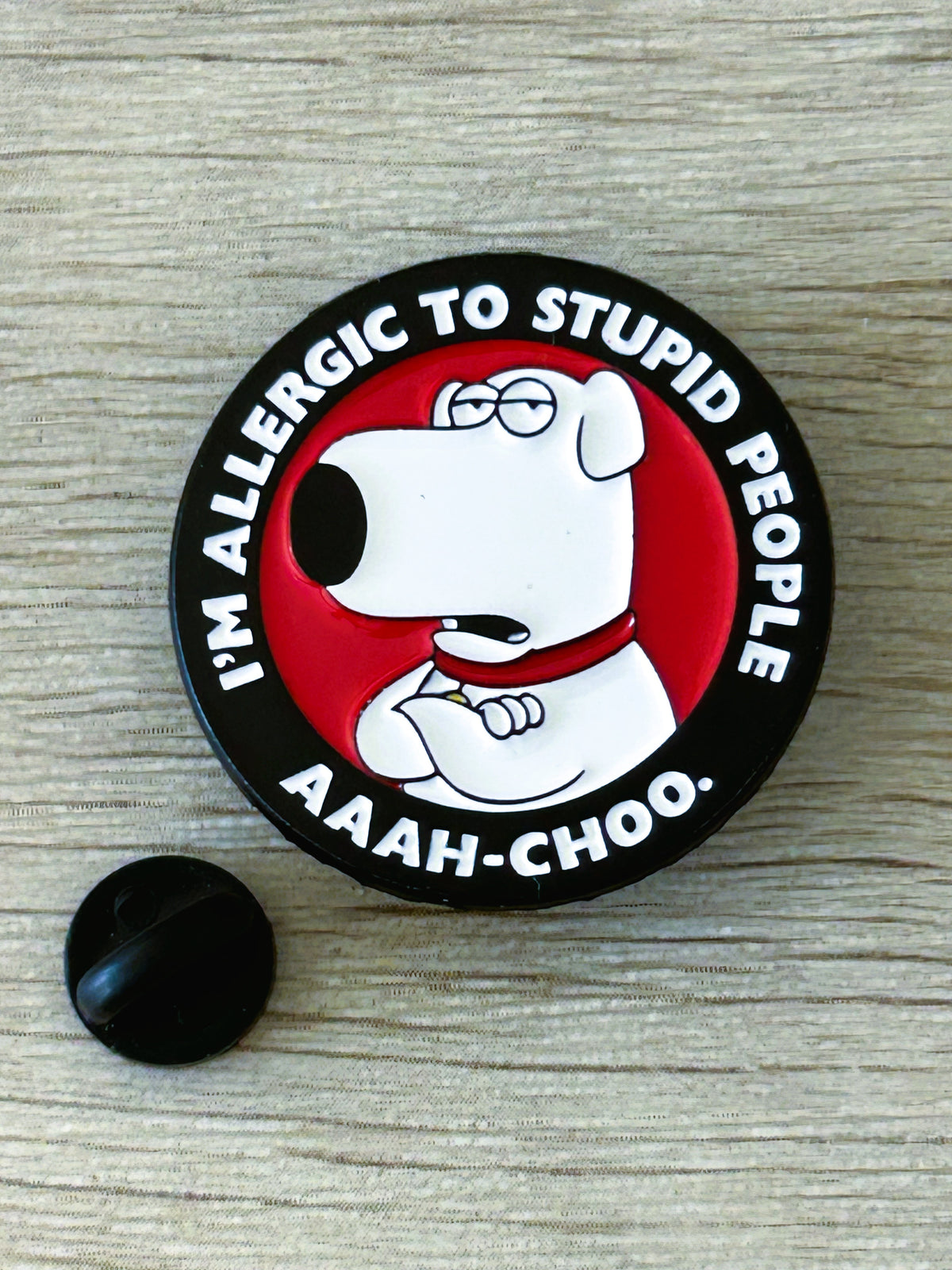 Broche ronde noire avec chien blanc rouge et visuel « AAaaH-CHOO » ; dos noir