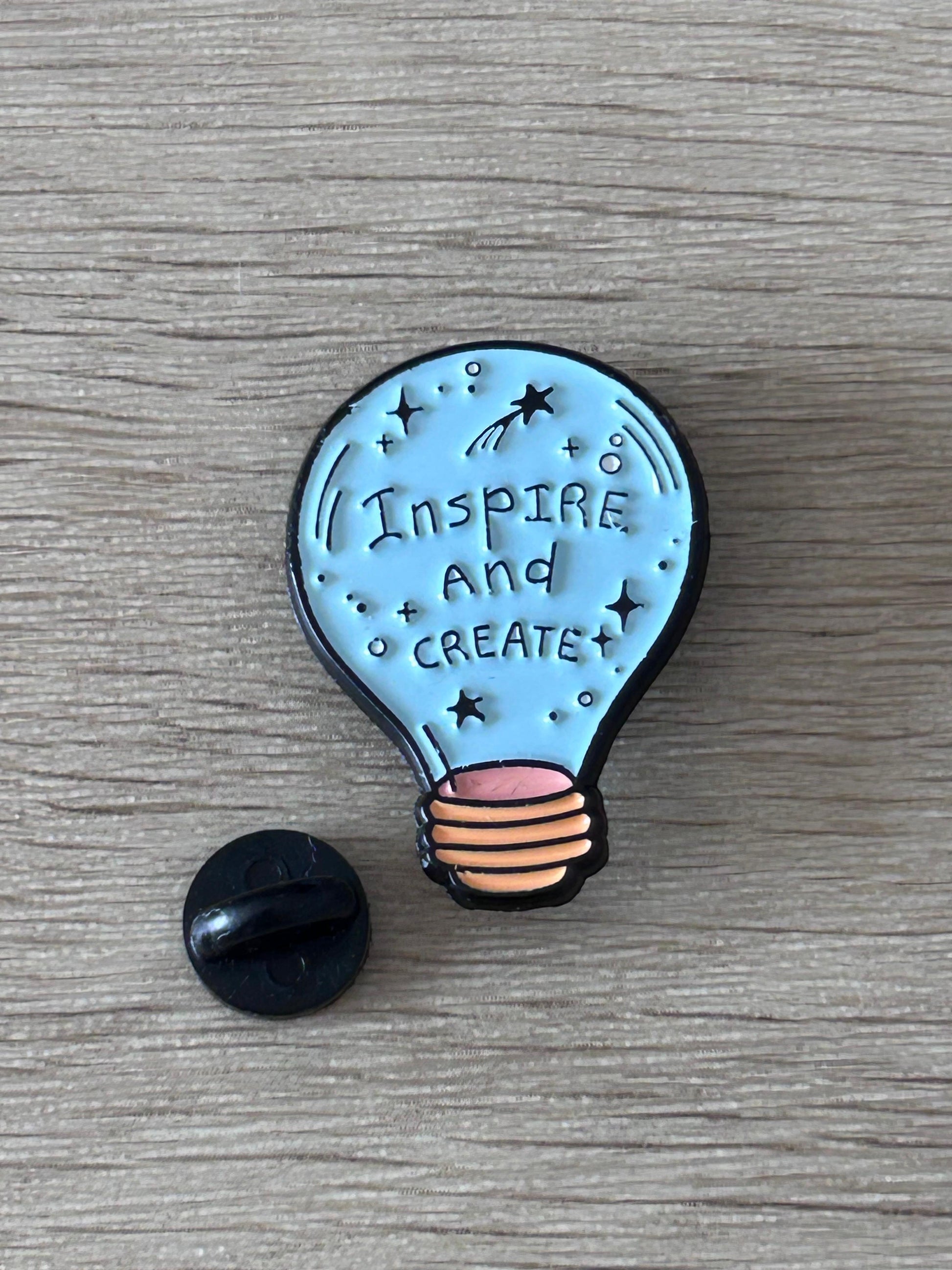 Broche ampoule bleue « Inspire and Create »; dos noir visible