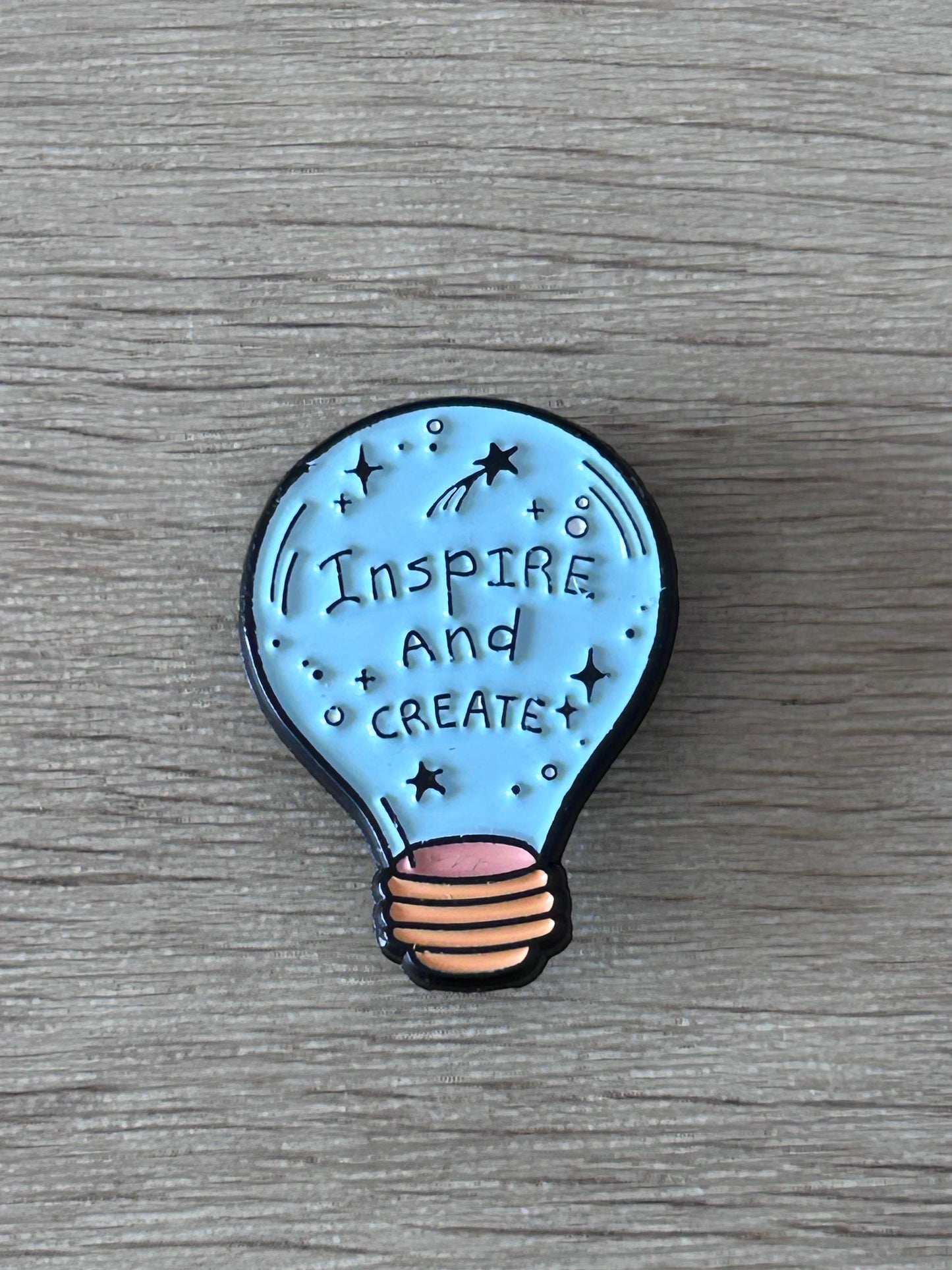 Broche ampoule bleue « Inspire and Create » avec étoiles, contour noir