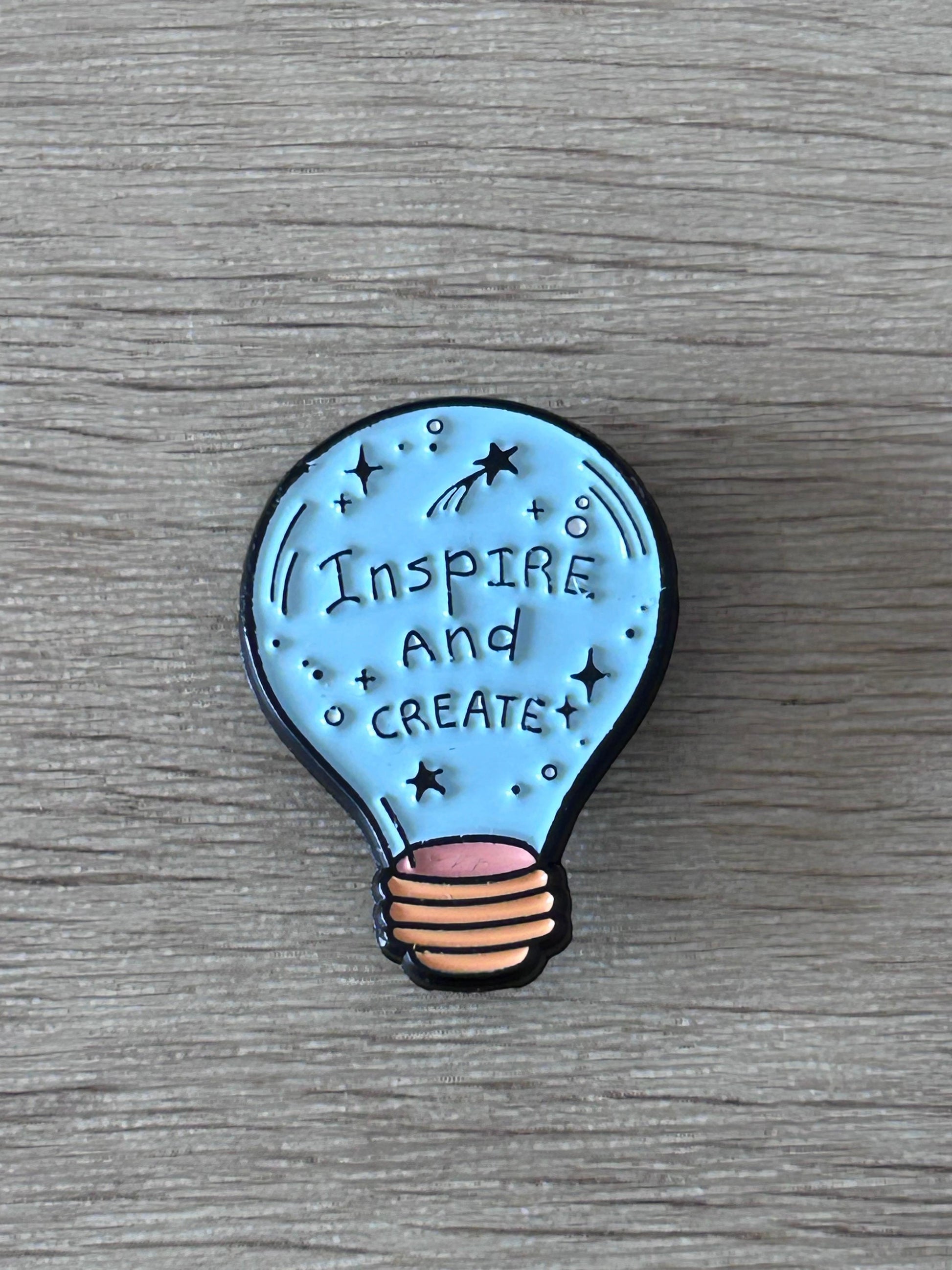 Broche ampoule bleue « Inspire and Create » avec étoiles, contour noir