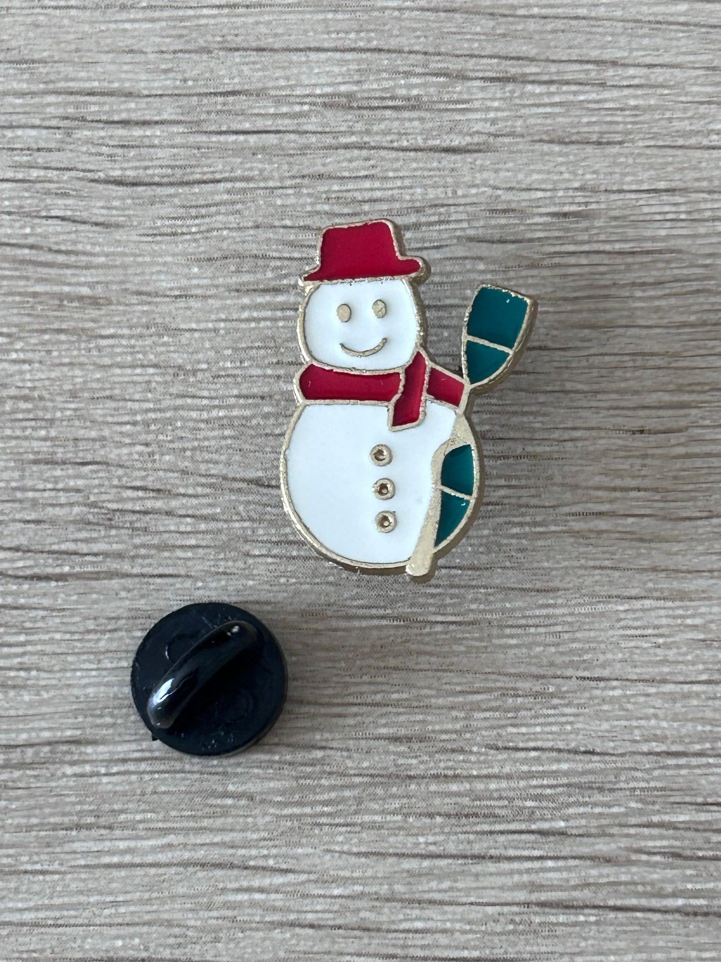 Broche bonhomme de neige émaillée avec dos noir rond : chapeau rouge, écharpe verte.