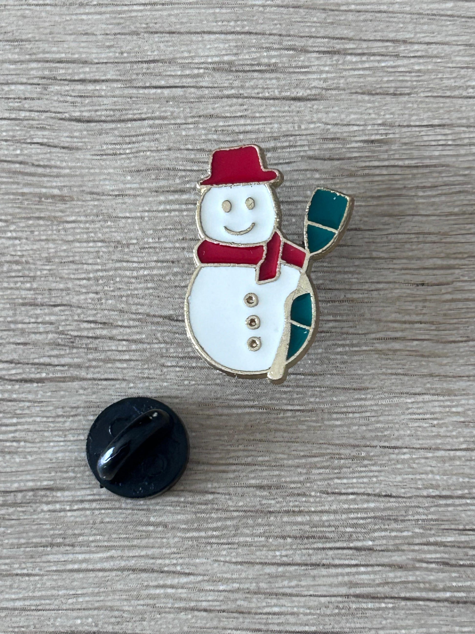 Broche bonhomme de neige émaillée avec dos noir rond : chapeau rouge, écharpe verte.
