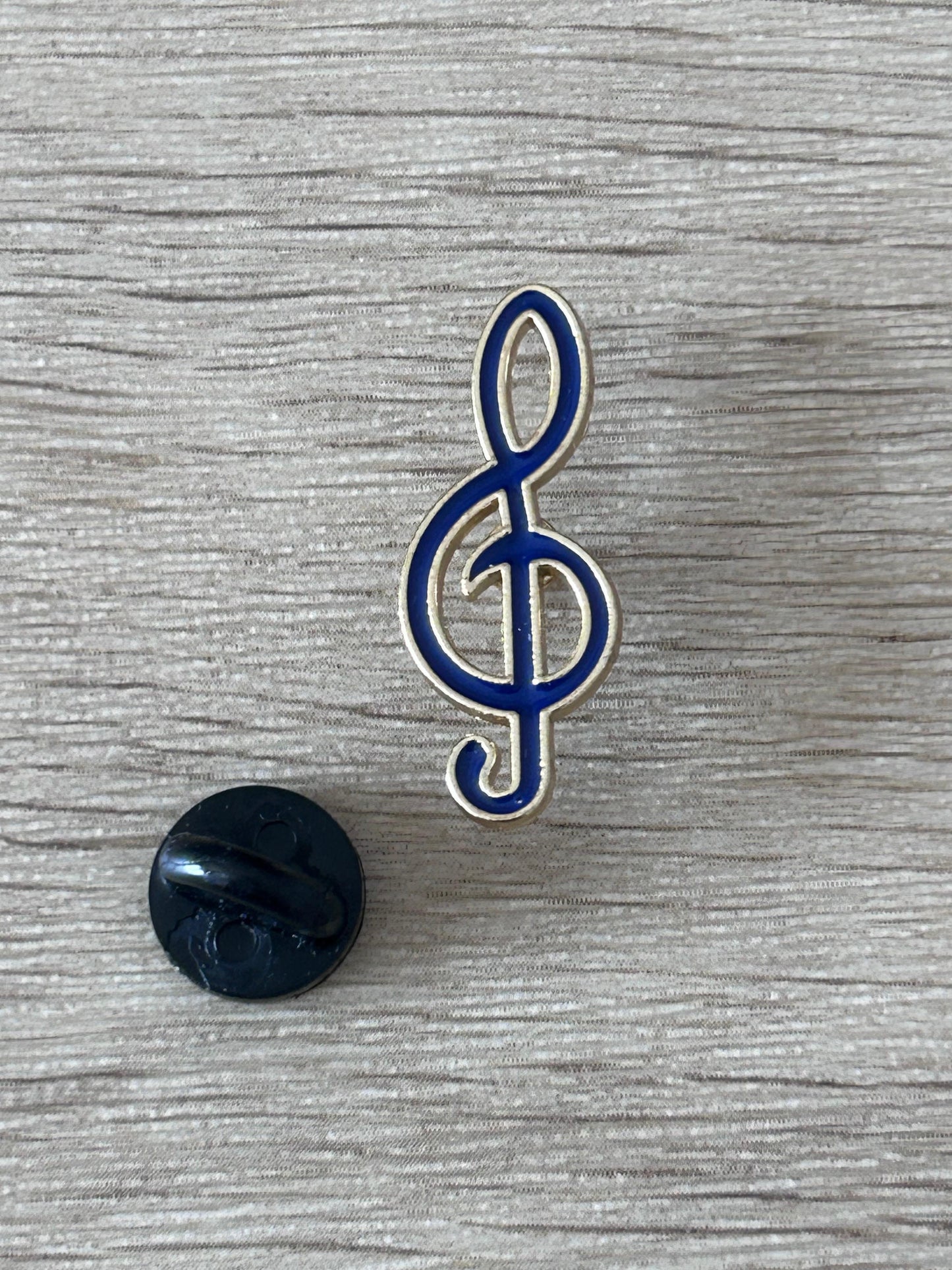 Pin's clé de sol émaillée bleu et blanche avec dos noir rond.