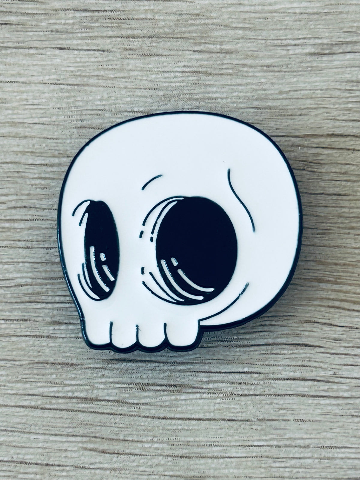 Pin tête de mort kawaii blanc, contour noir, yeux dessinés style mignon