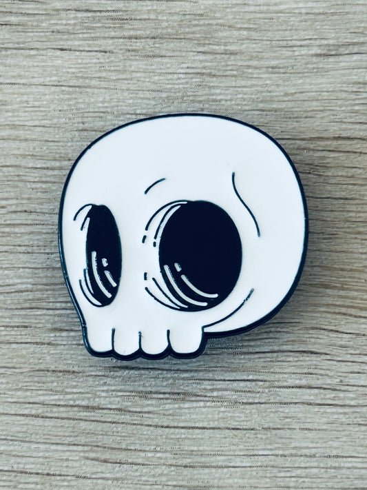 Pin tête de mort kawaii blanc, contour noir, yeux dessinés style mignon