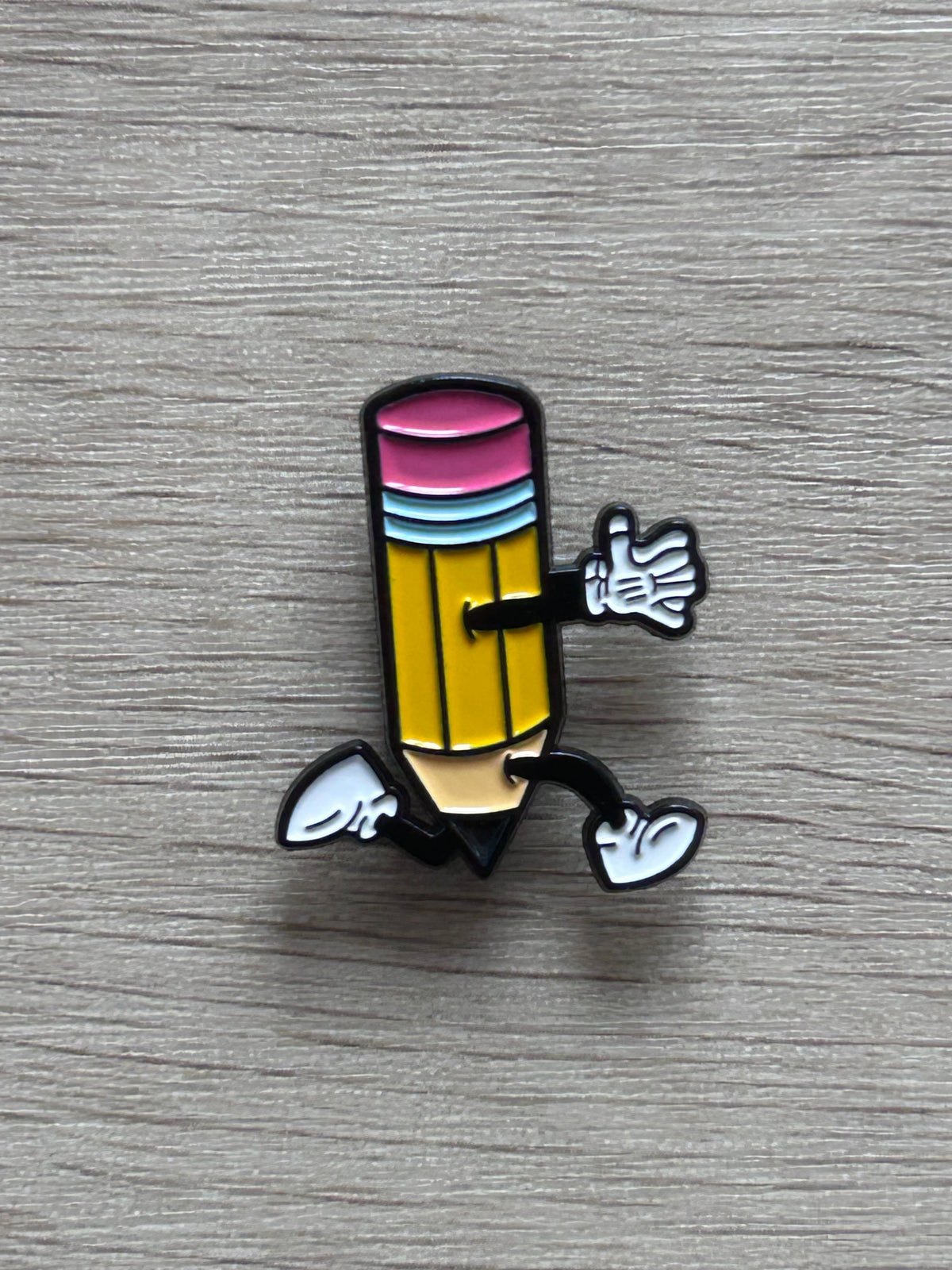 Pin's crayon jaune coloré sur fond en bois