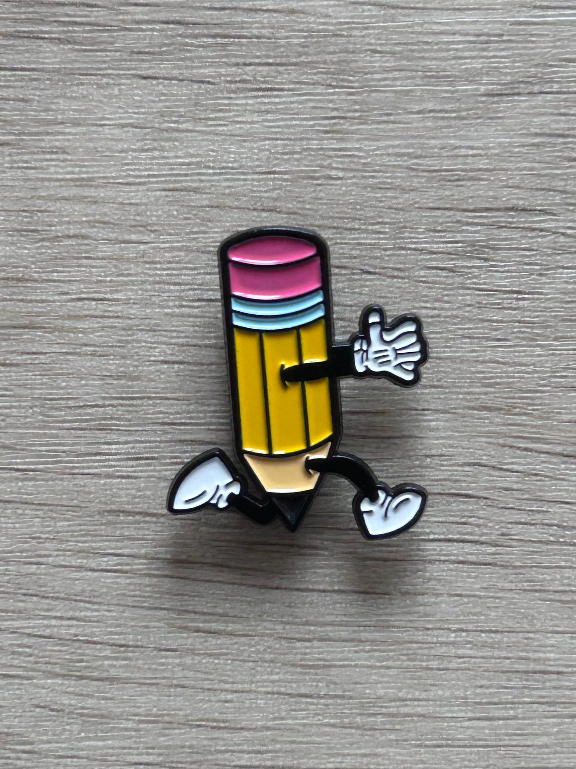 Pin's crayon jaune coloré sur fond en bois
