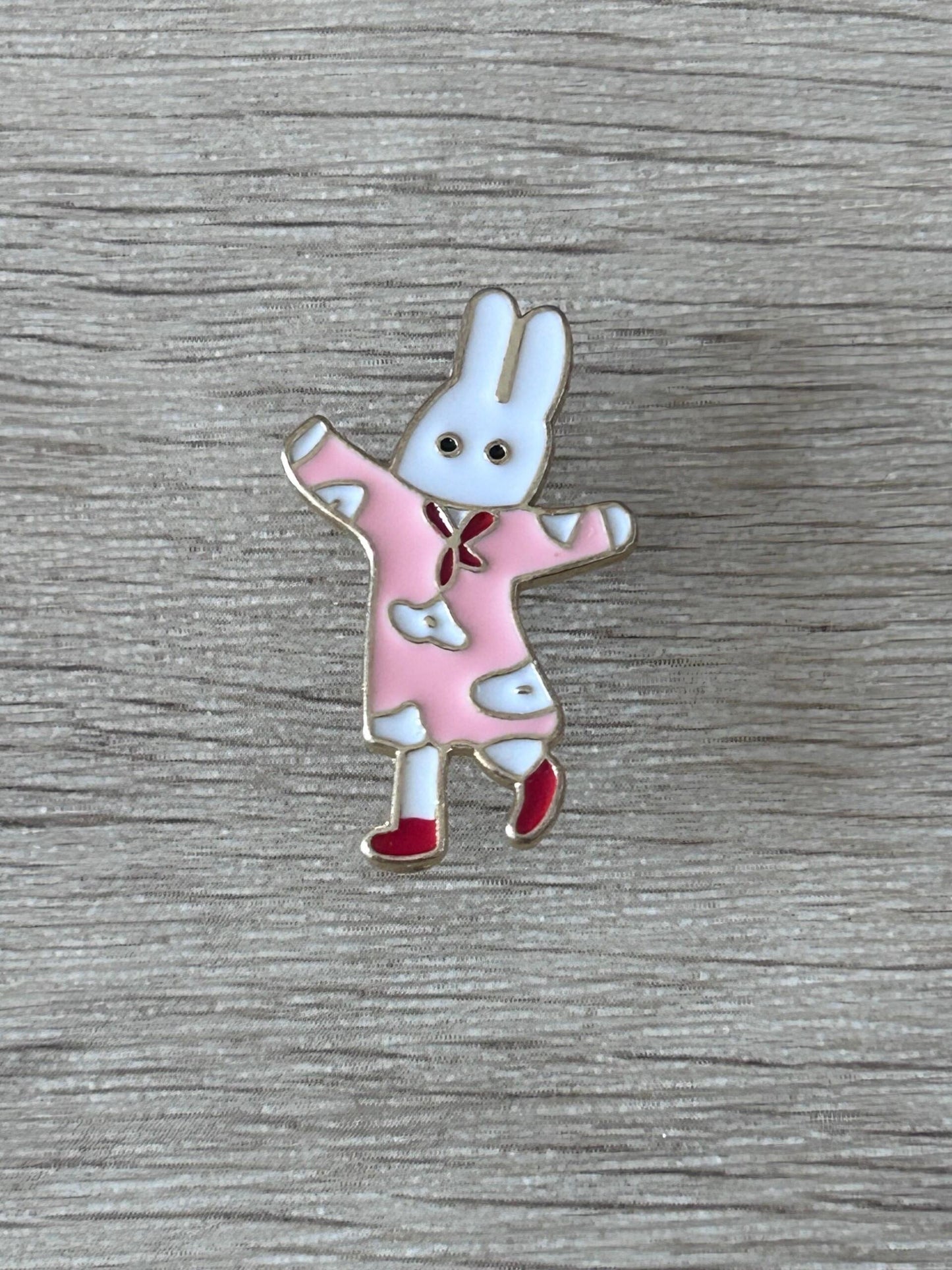 Pin's de lapin danseur en robe rose, bras levés et chaussures rouges