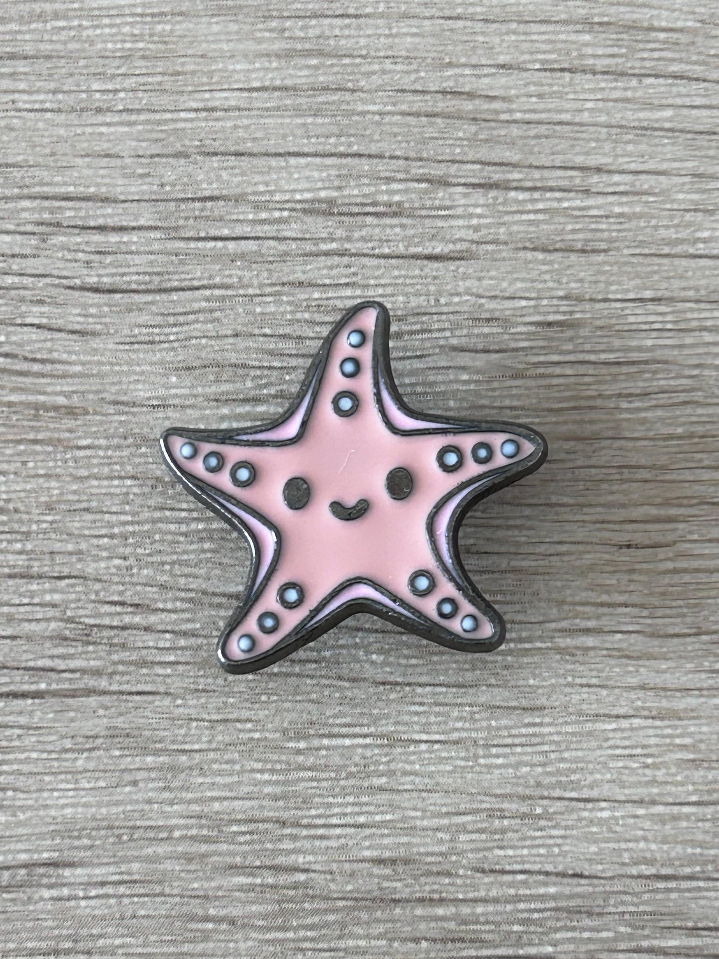 Pin's en forme d’étoile de mer kawaii rose, contour noir, points bleus.