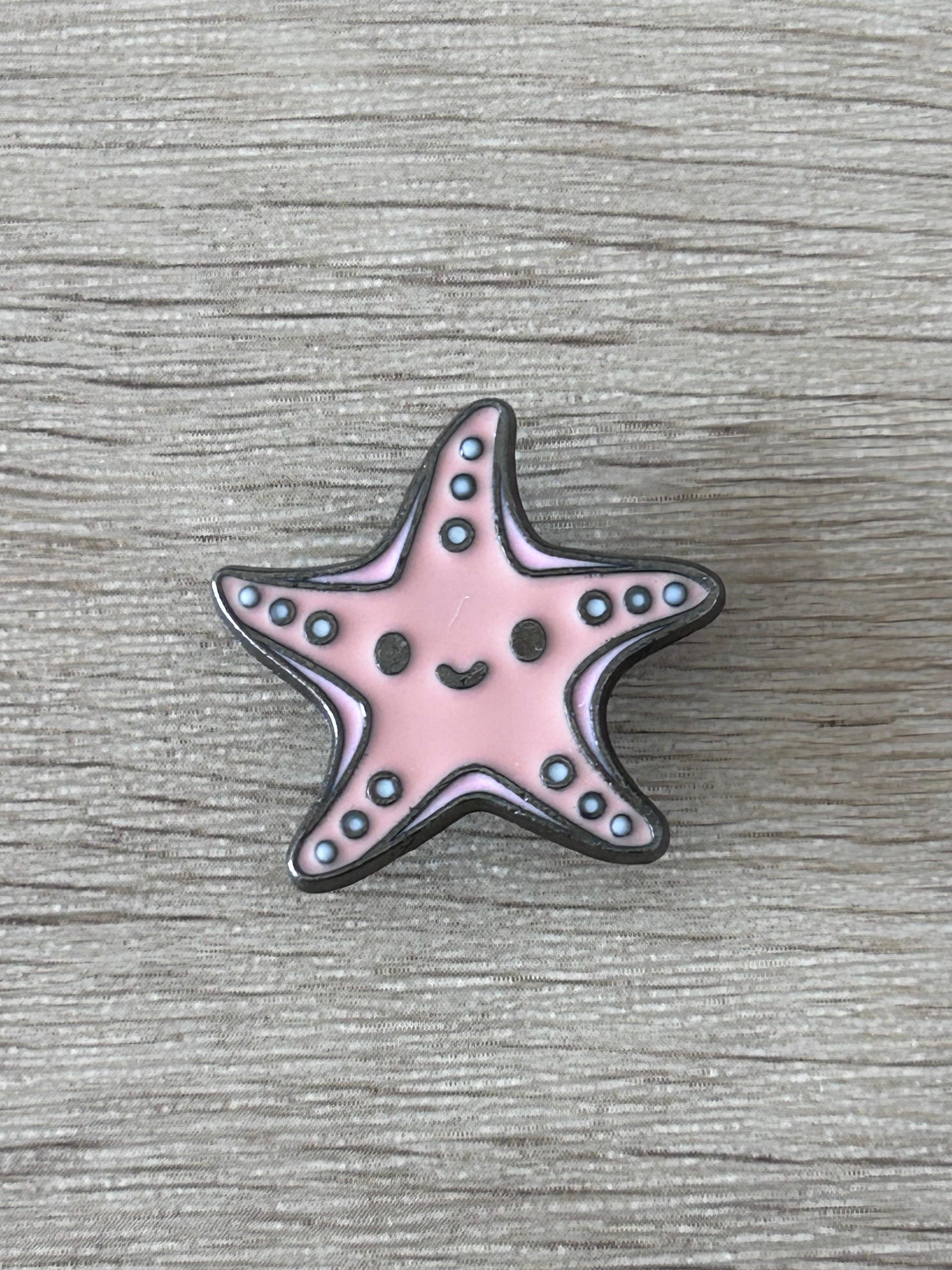Pin's en forme d’étoile de mer kawaii rose, contour noir, points bleus.