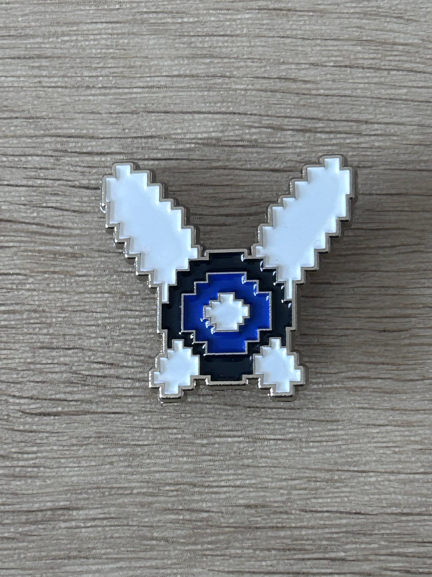 Broche fée pixel art bleu marine et bleu clair, ailes en V, contour argenté.