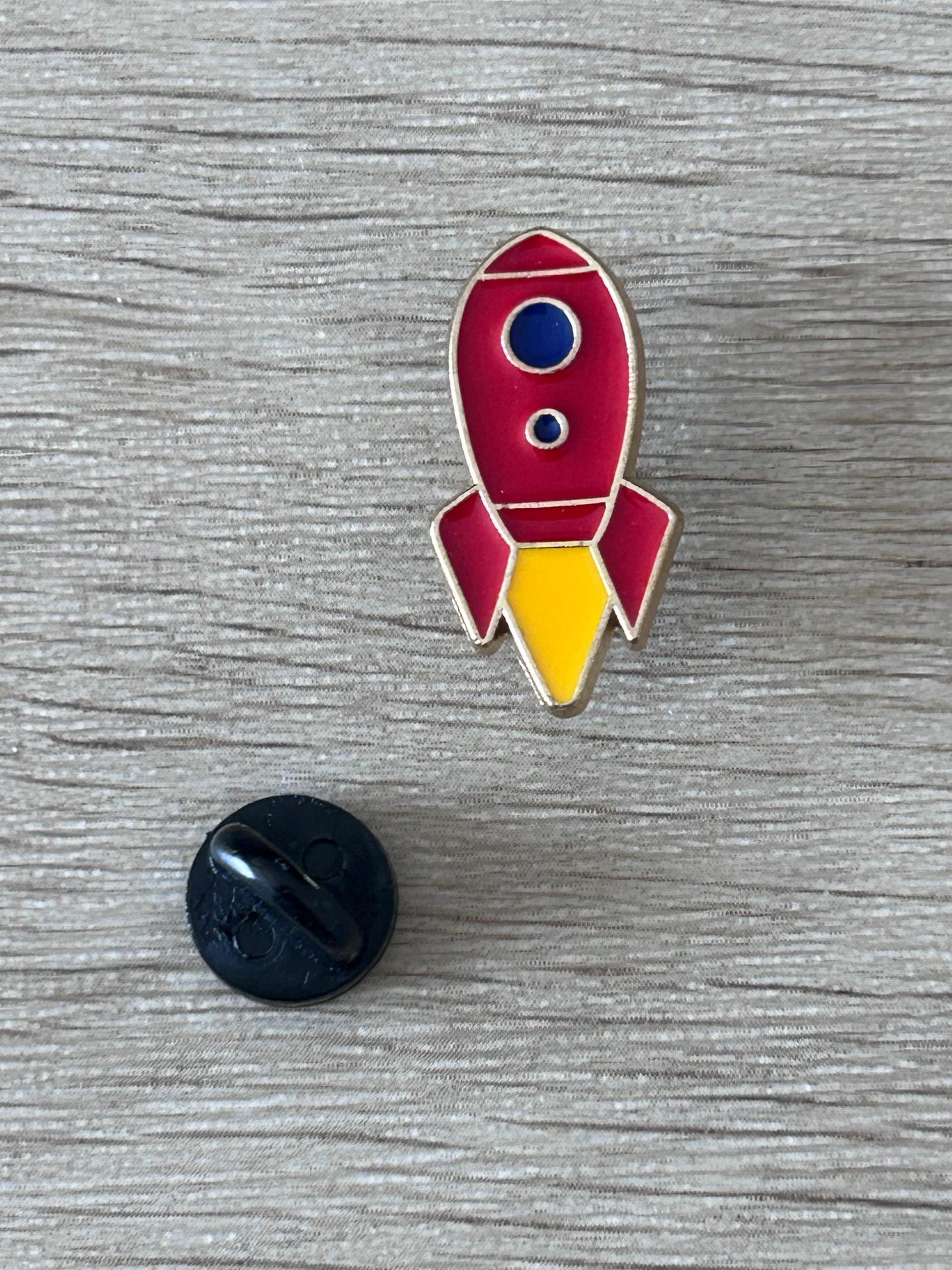 Pin fusée rétro émaillée rouge, fenêtre bleue, dos noir visible