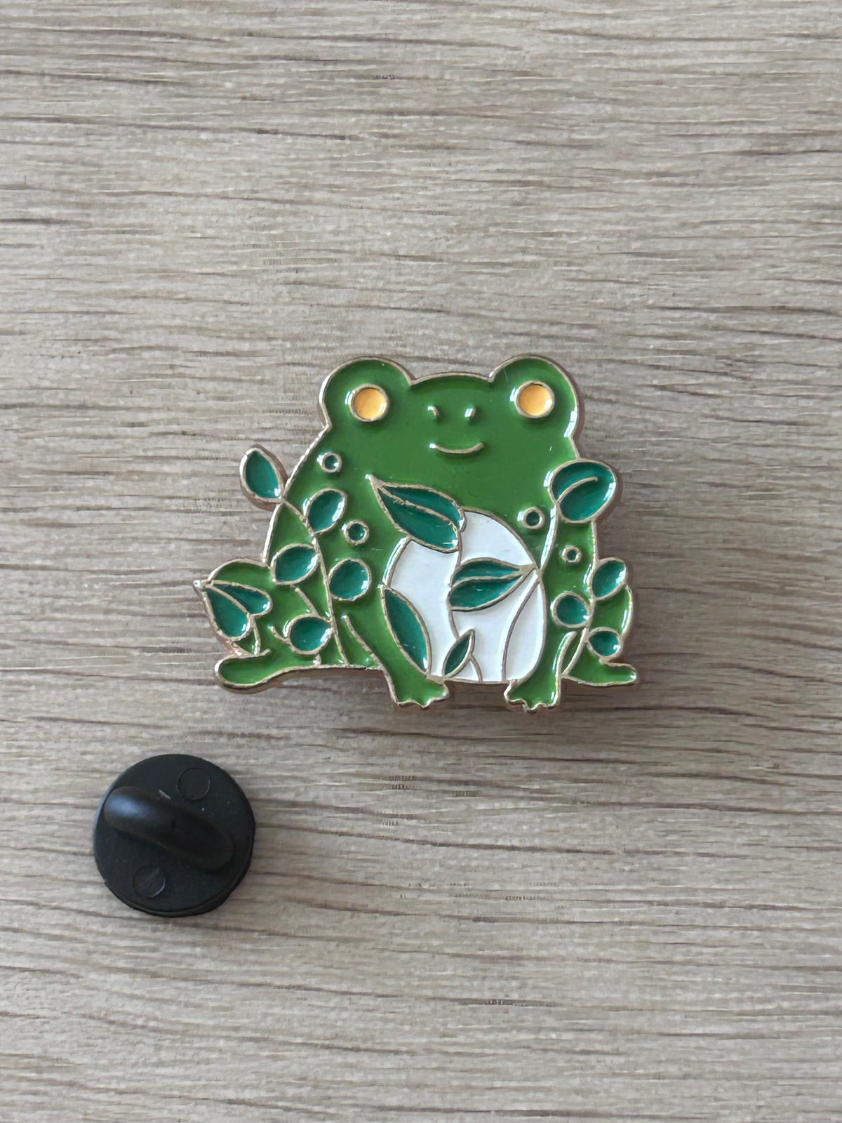 Pin grenouille verte émaillée avec feuilles, arrière noir visible