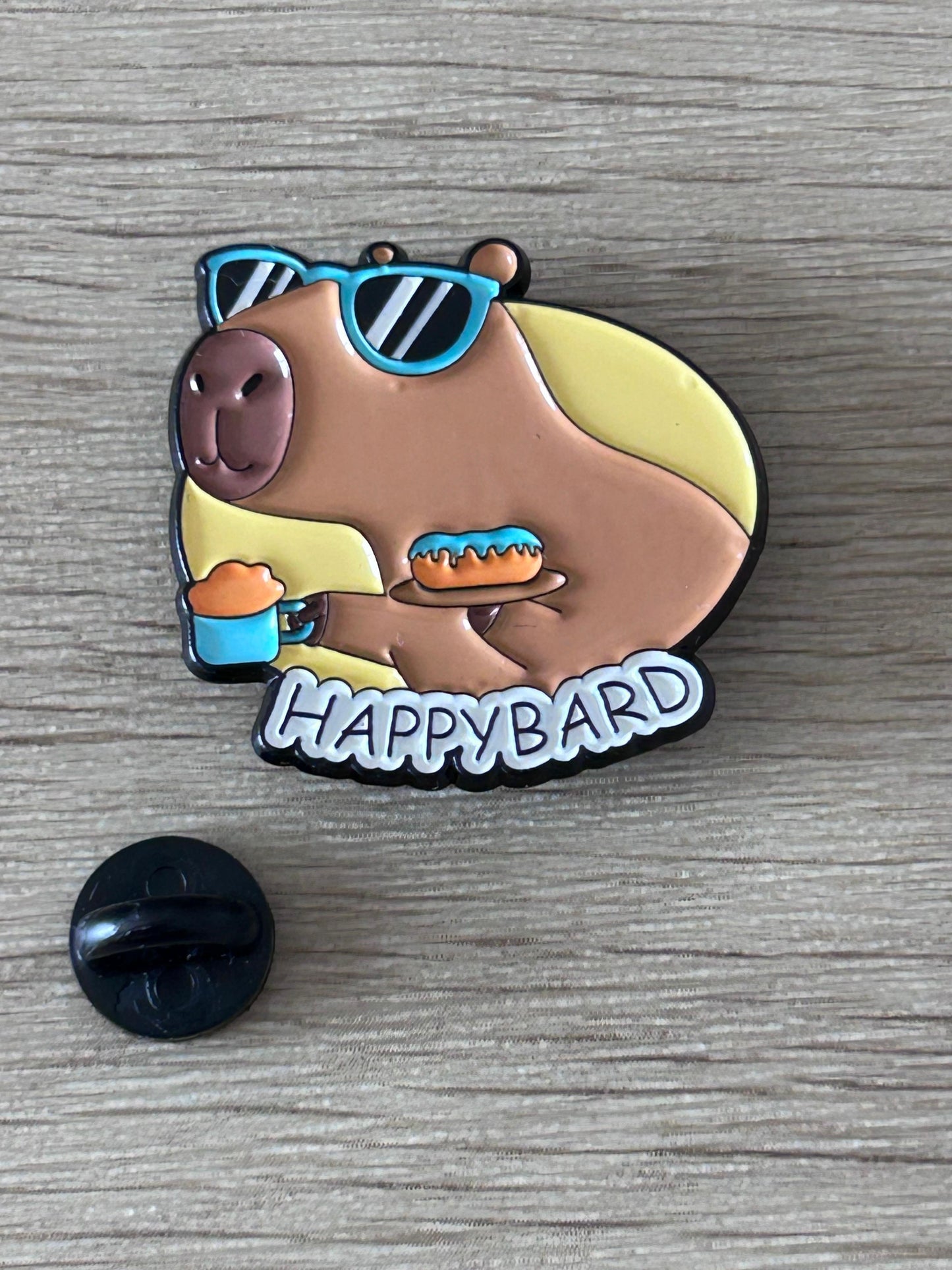 Pin capybara «Happybard» émaillé marron, lunettes bleues et boisson.