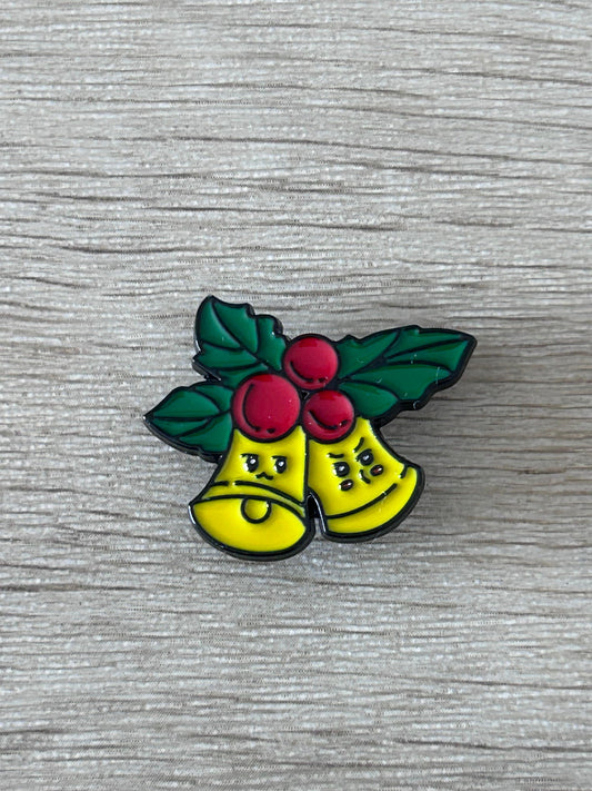 Pin's cloches de Noël kawaii : deux clochettes jaunes, feuilles vertes et baies rouges.