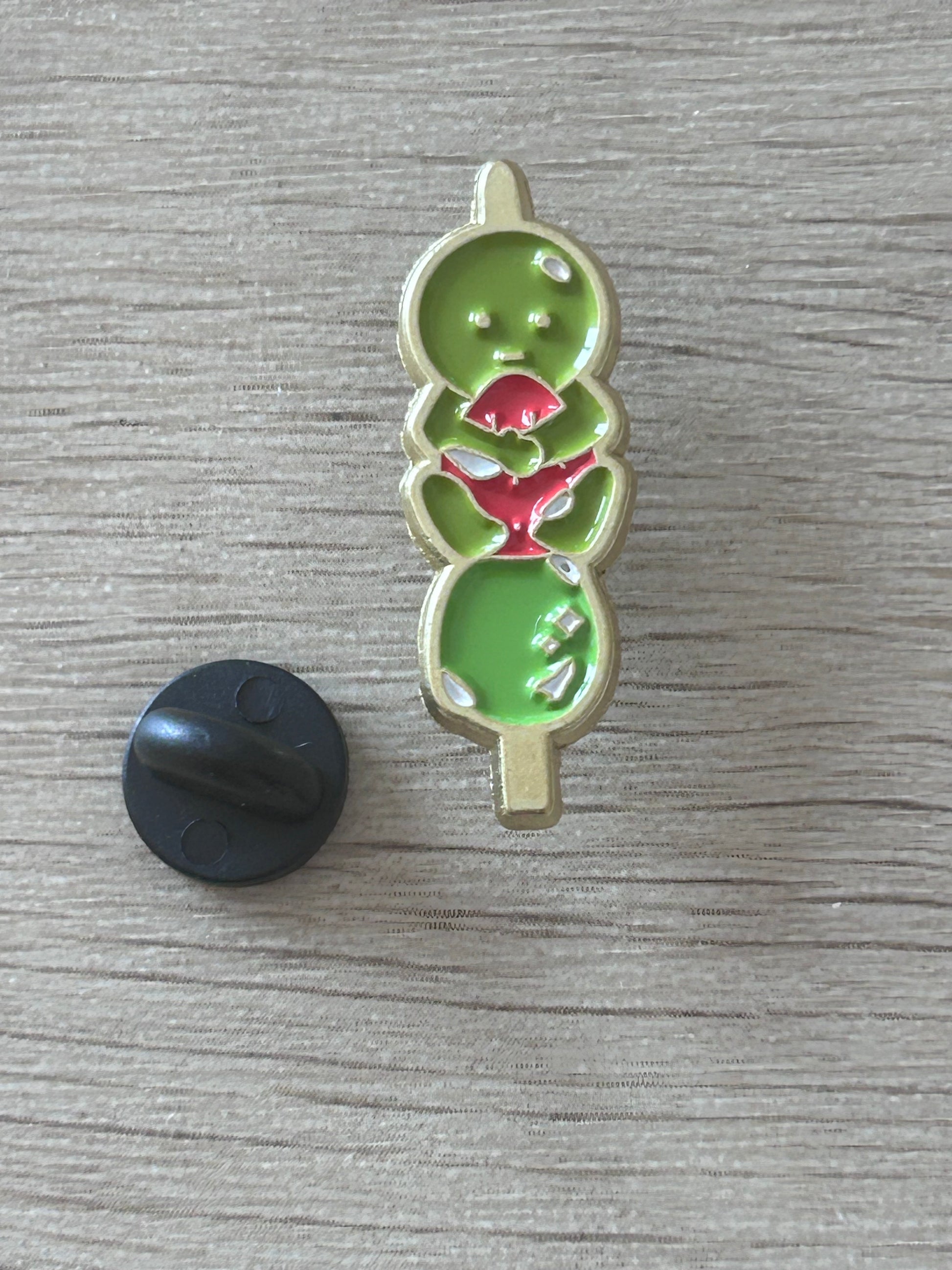 Pin émaillé vert en forme de personnage kawaii, détails rouges en forme de fraise