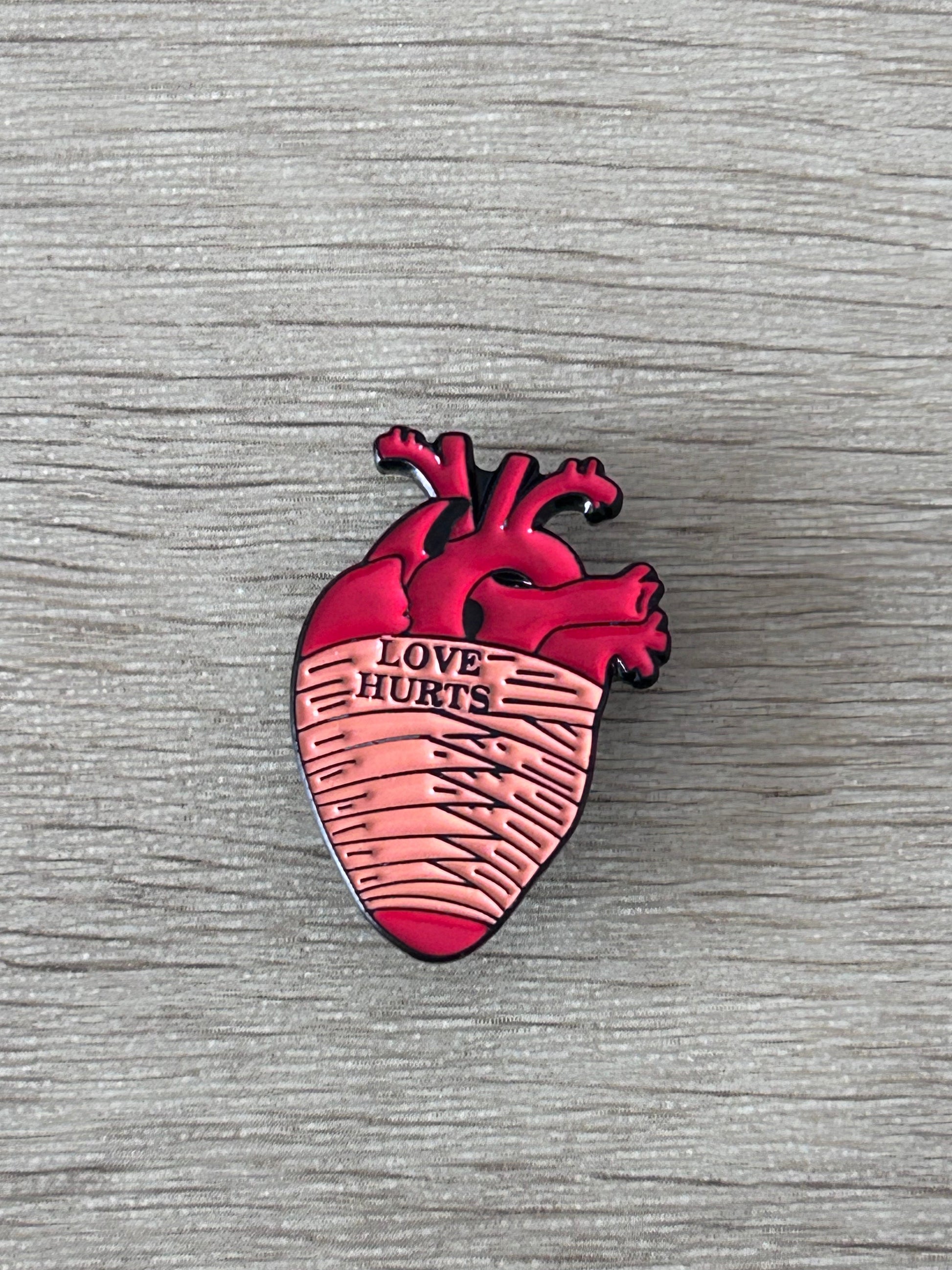Pin cœur anatomique rouge avec texte « Love Hurts »