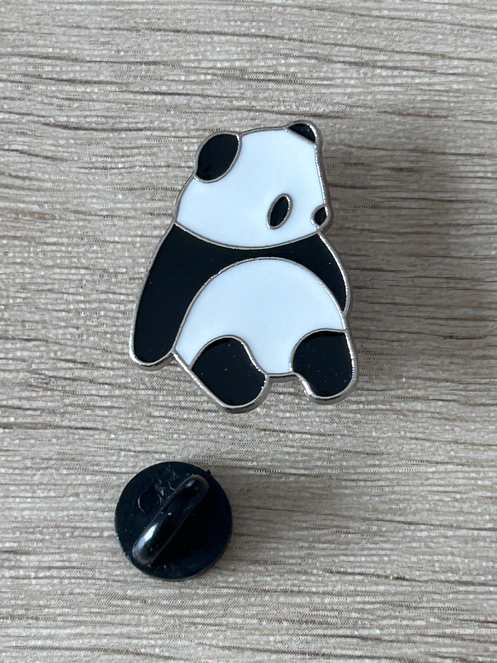 Pin's panda assis émaillé noir et blanc, attache arrière noire visible.